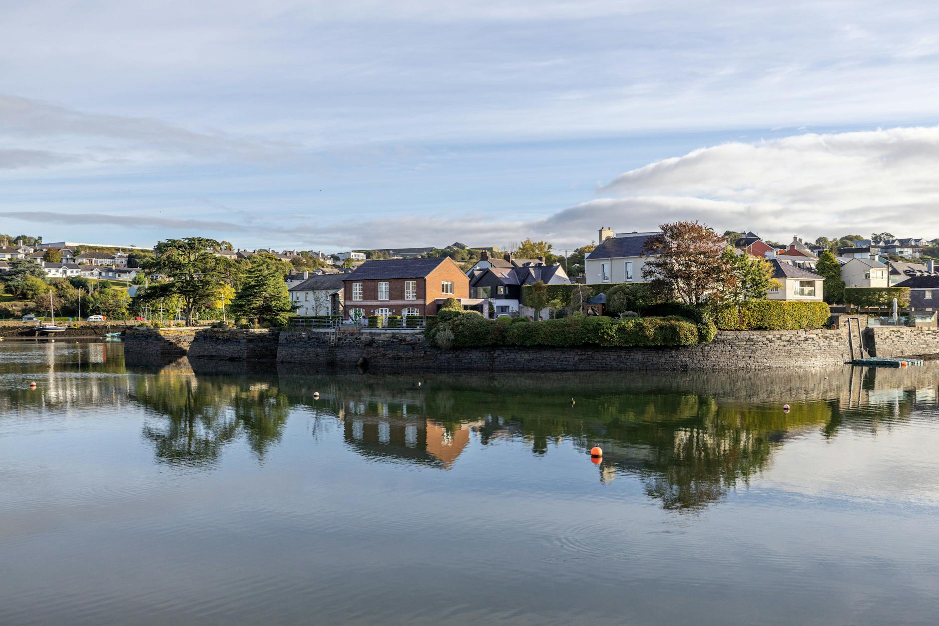 Charming waterfront houses reflected on calm water in Kinsale, County Cork, Ireland.