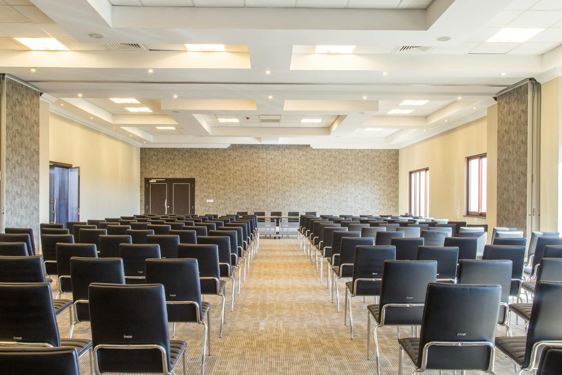Spacious empty conference room with modern design and neatly arranged black chairs.