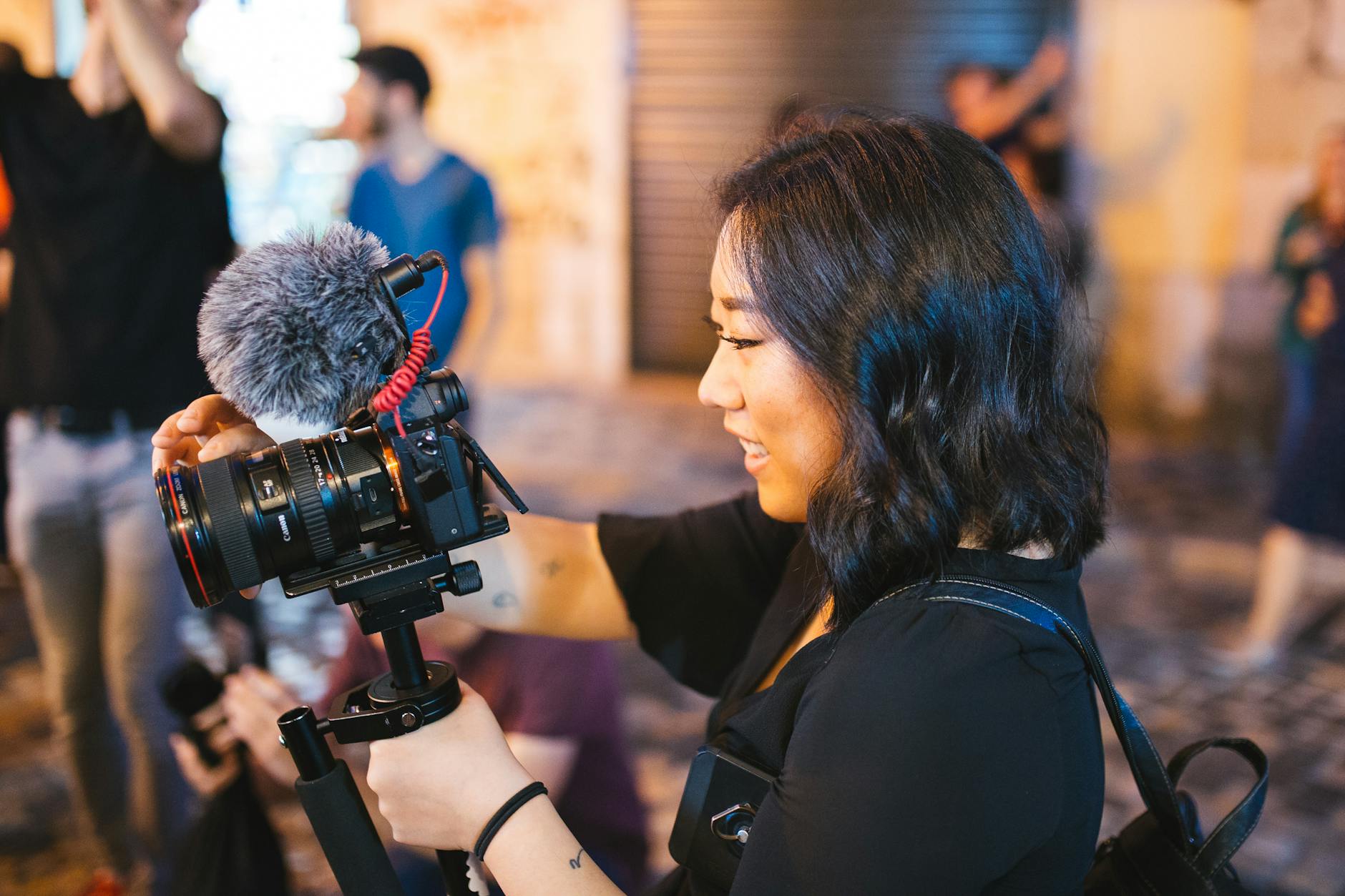 A woman using a DSLR camera with a microphone outdoors.