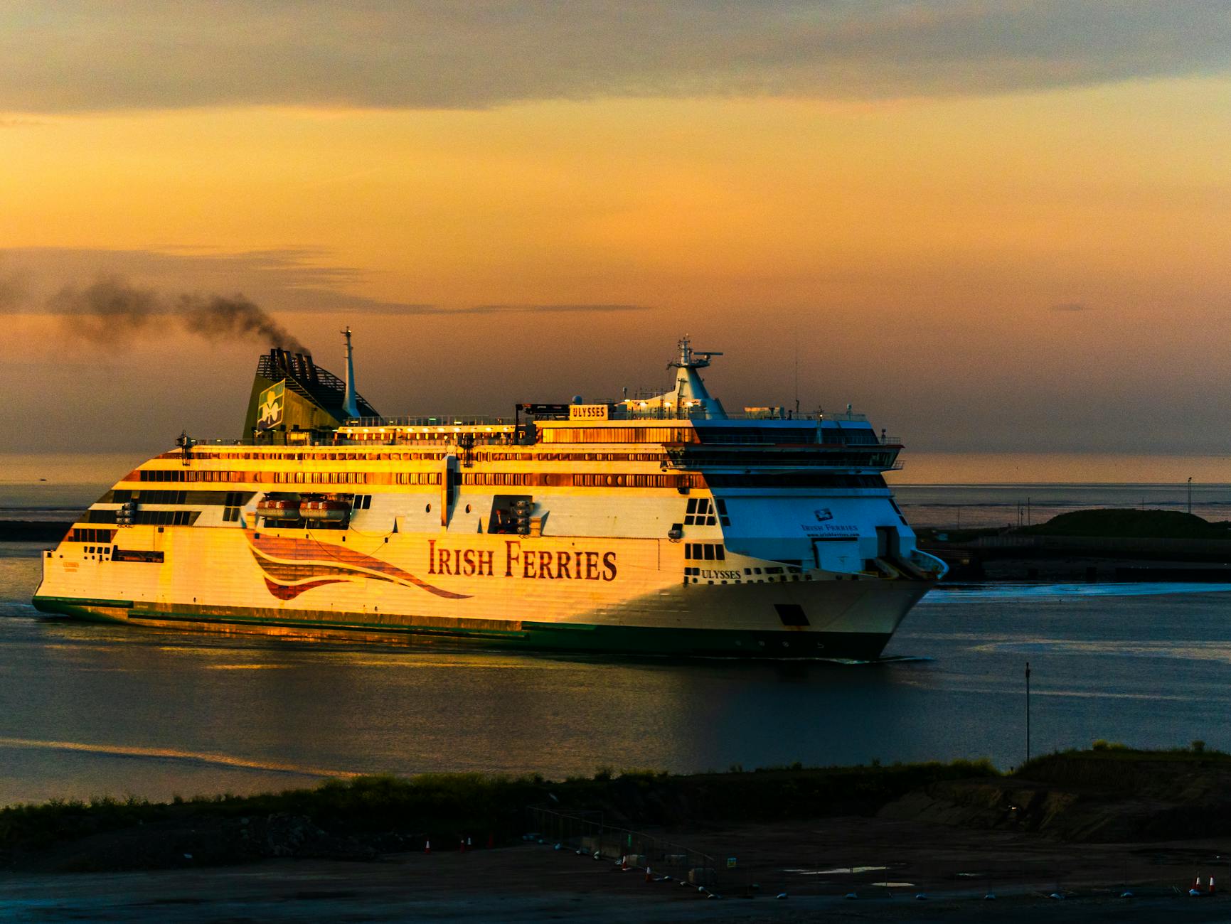 Irish Ferries cruise ship sails at sunset, with vibrant skies reflecting on calm waters.