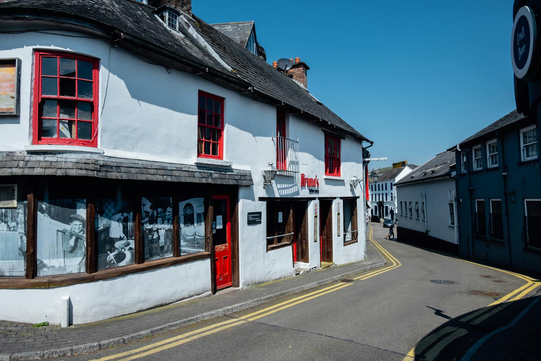 Explore the quaint streets of Kinsale, Ireland with this historic white building under a clear blue sky.