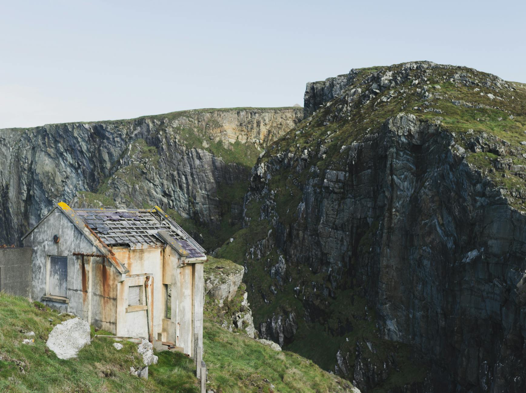 Rustic abandoned house perched on scenic cliffs in Cork, Ireland.