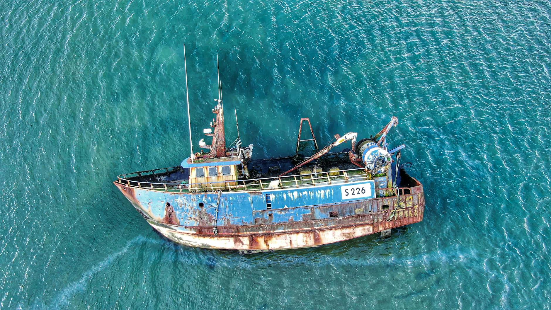 Drone shot of a rusty fishing boat in clear Irish waters.