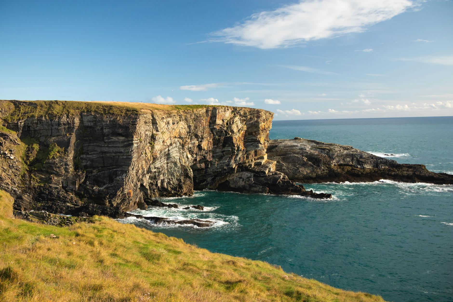 Gorgeous cliffside view overlooking the ocean in County Cork, Ireland, under a clear blue sky.
