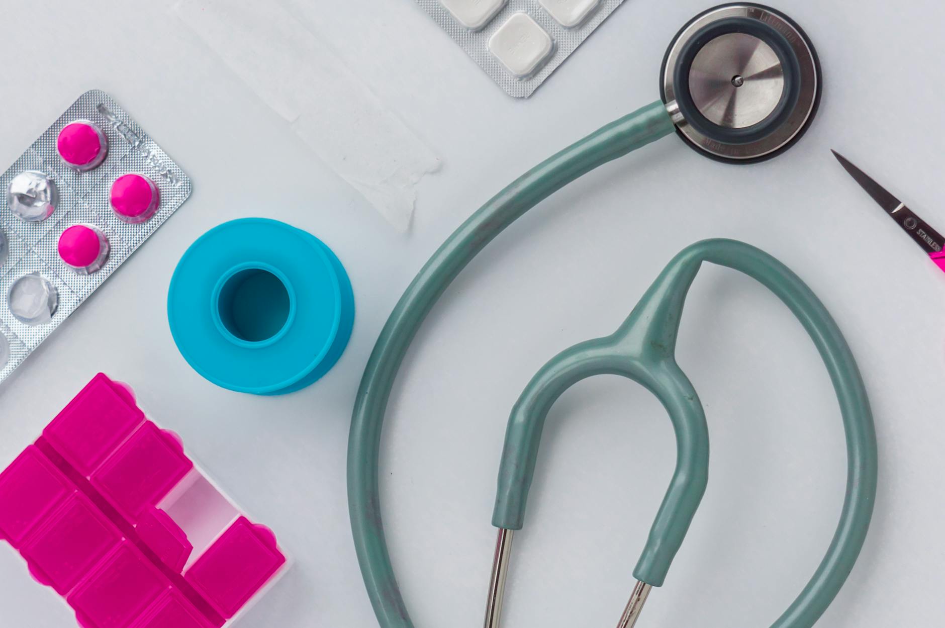 Overhead shot of medical supplies including stethoscope, pills, and scissors.