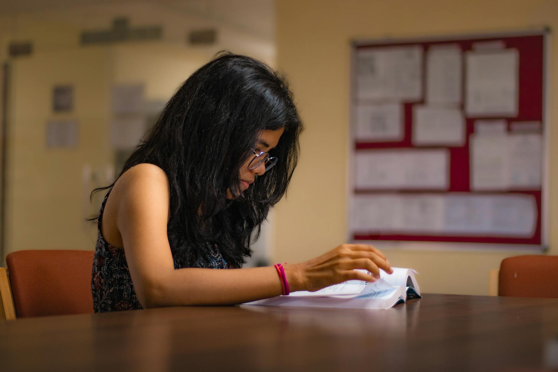 Student reading in a New Delhi library for presentation and materials planning.