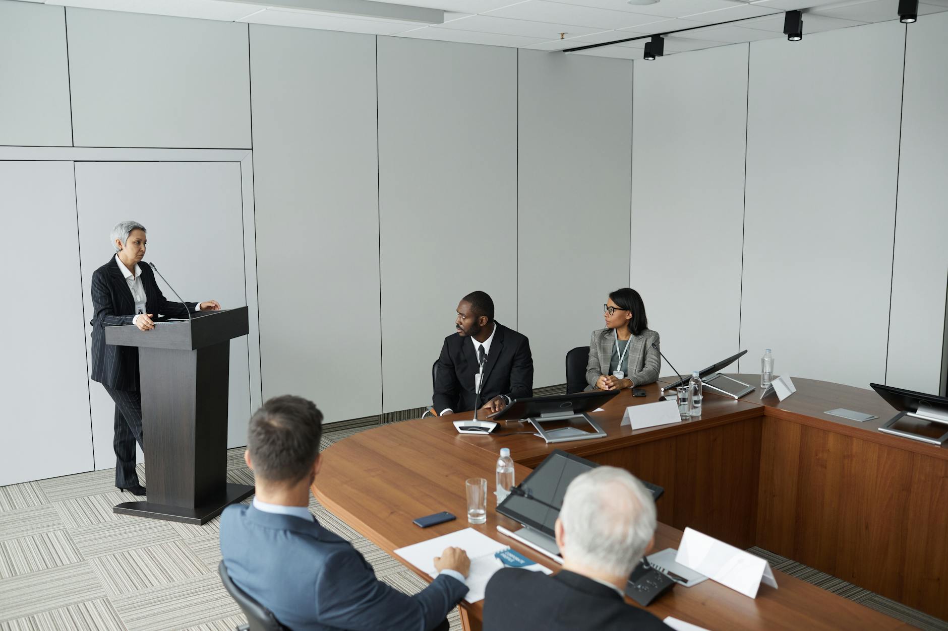 Formal meeting speaker and audience for Delhi conference travel report planning.