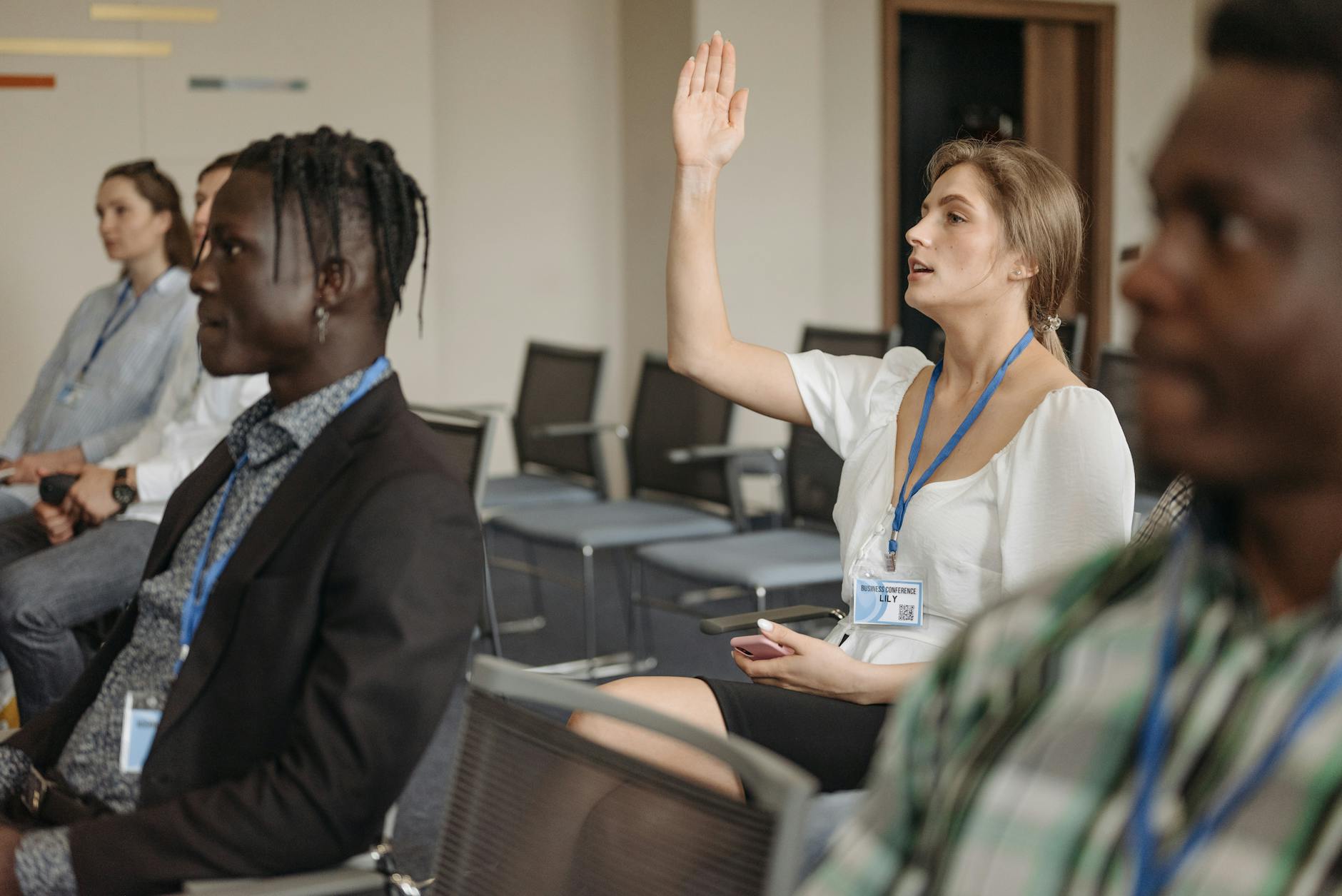 Woman raising a hand during a conference for Delhi networking planning.