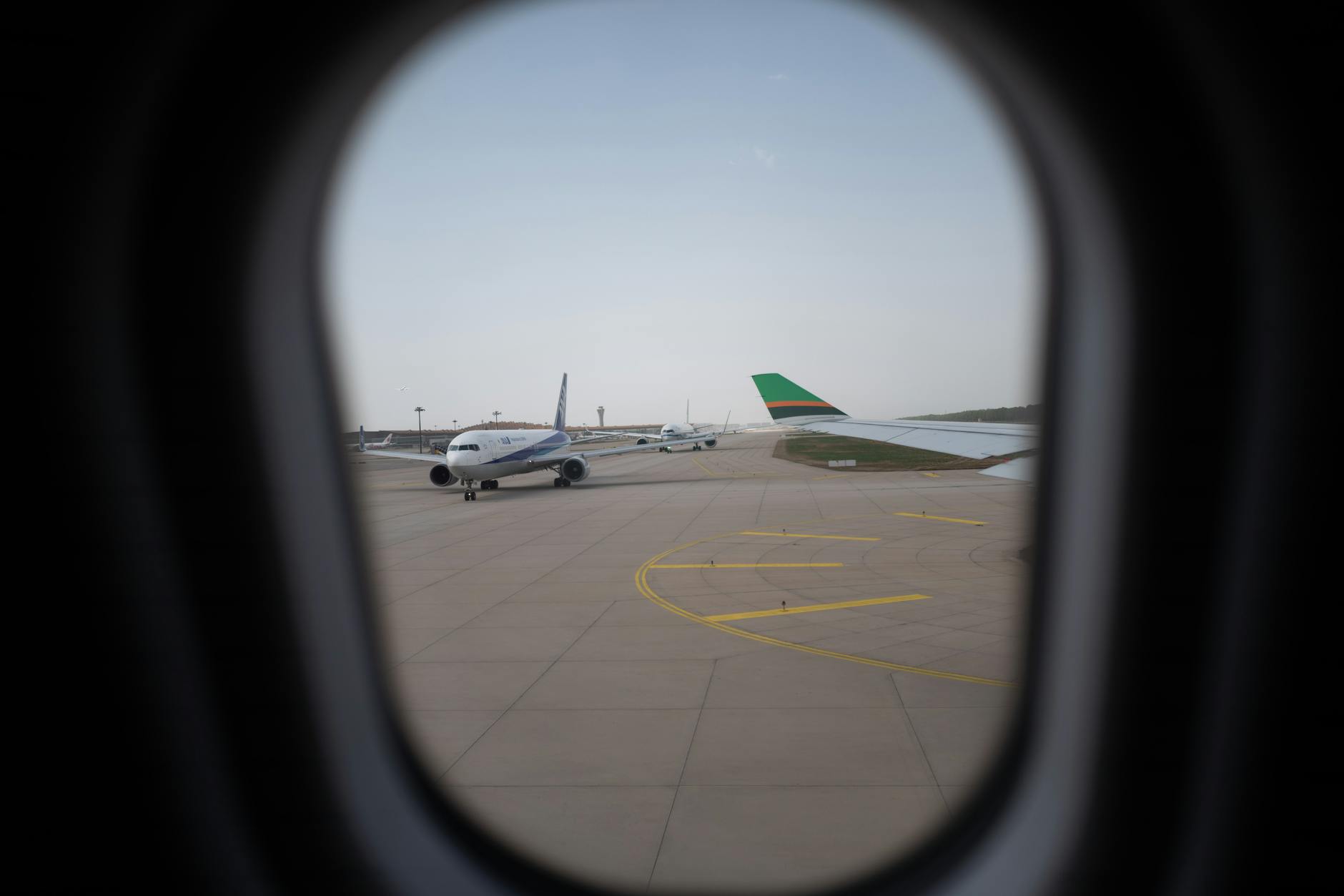 Airplane viewed through an airport window for Delhi family arrival planning.