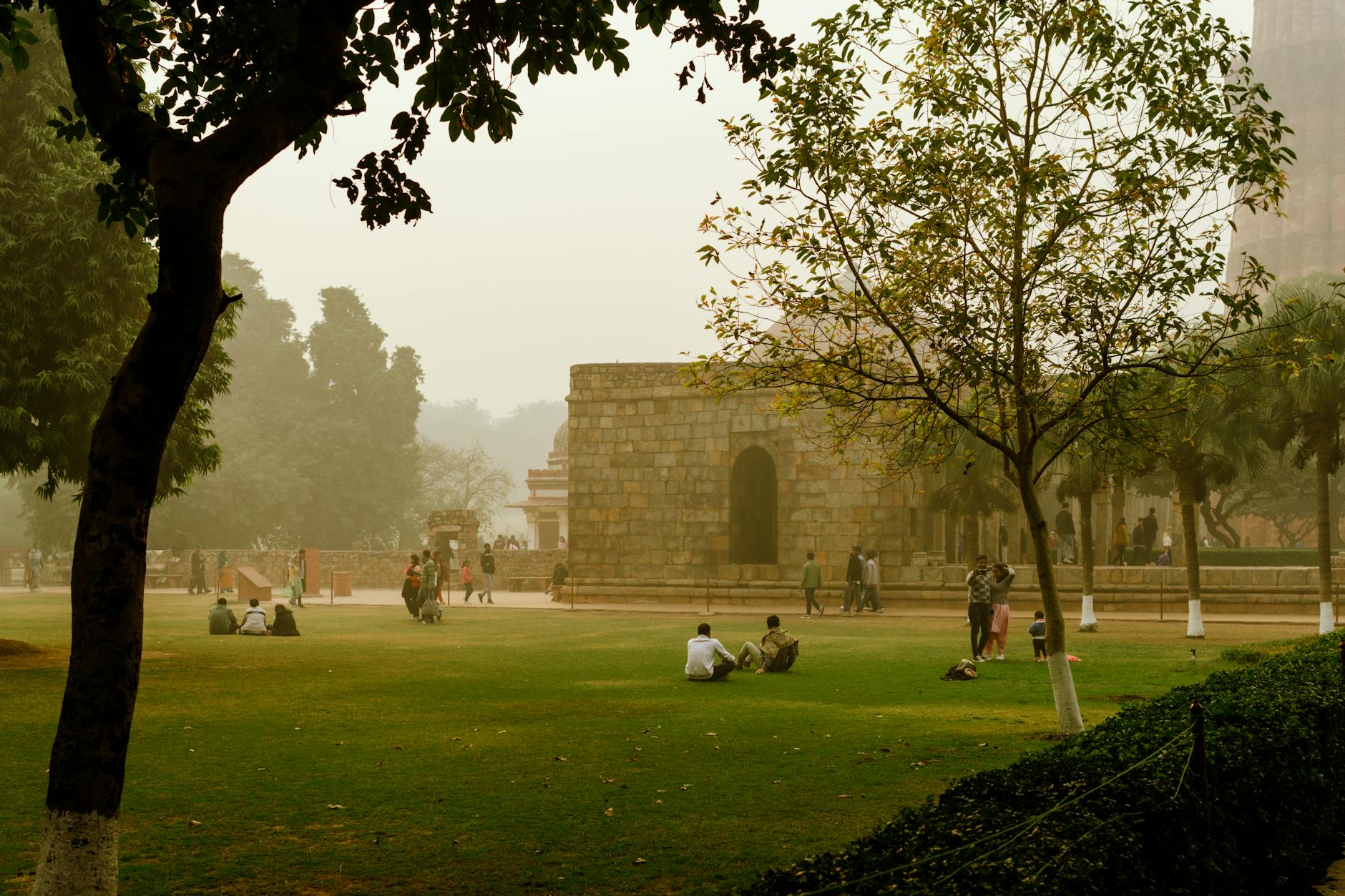 People relaxing near Qutb Minar park in Delhi for family hotel-area planning.