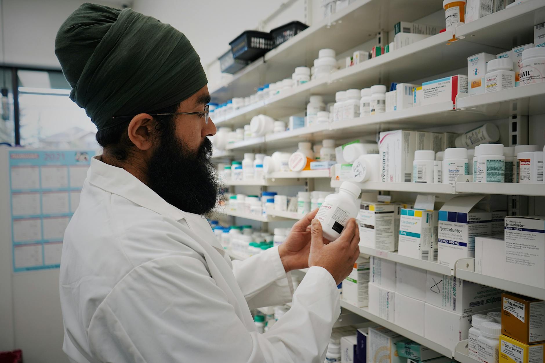 Pharmacist organizing medicine shelves for travel support planning.