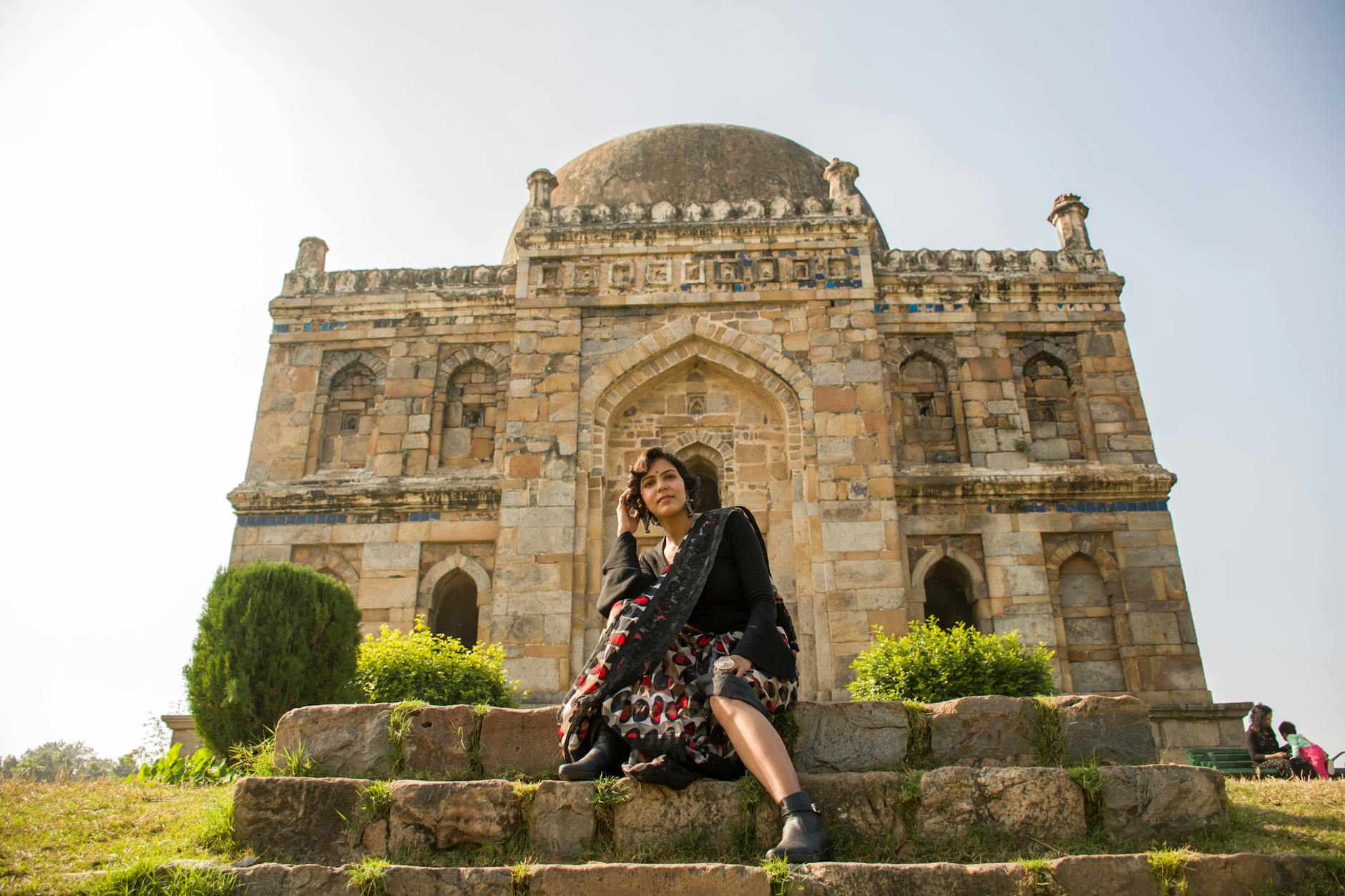 Woman seated near Shish Gumbad in Delhi for woman traveler planning.