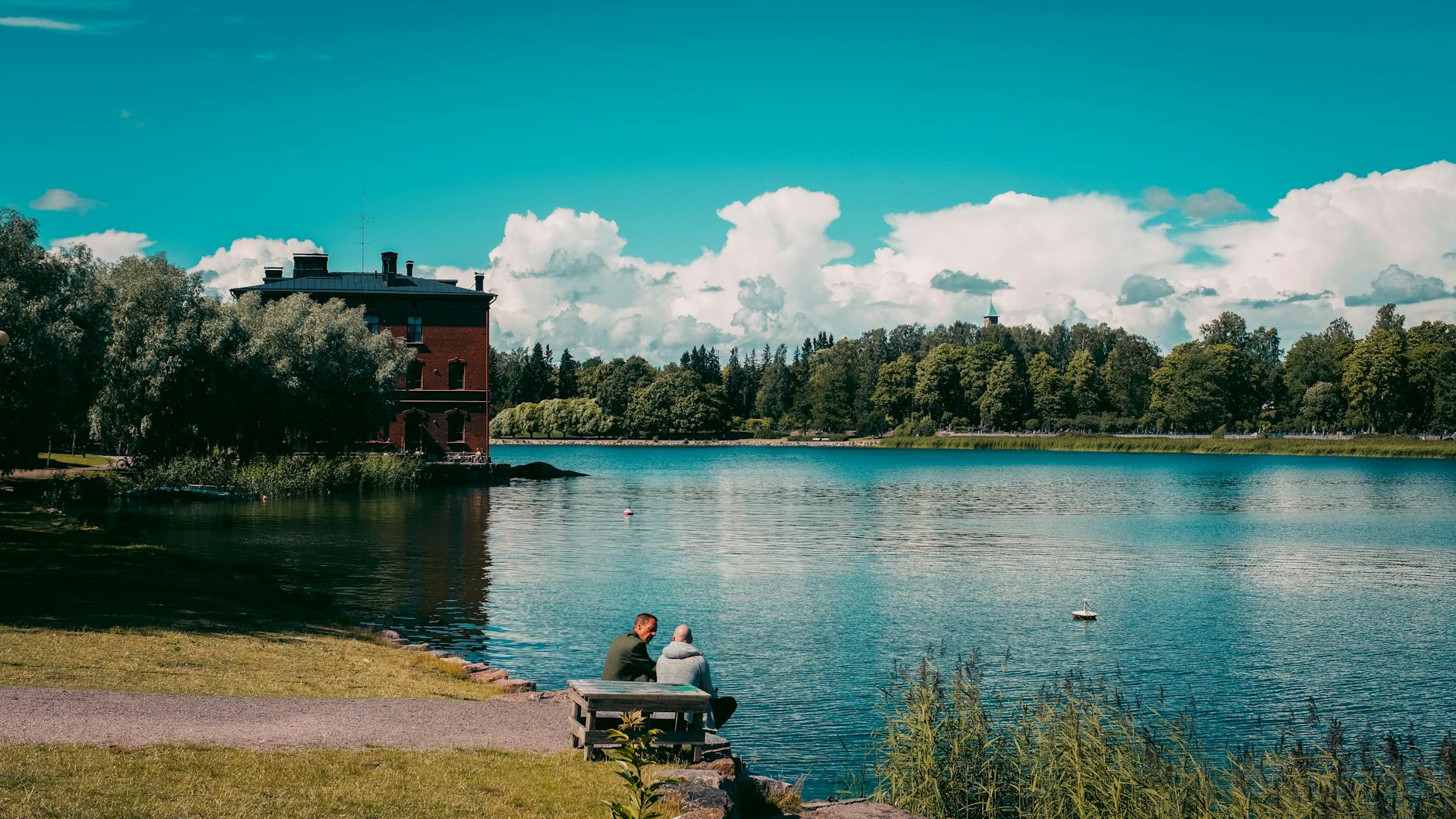 People by a Helsinki lake for budget pacing and hidden-cost planning.