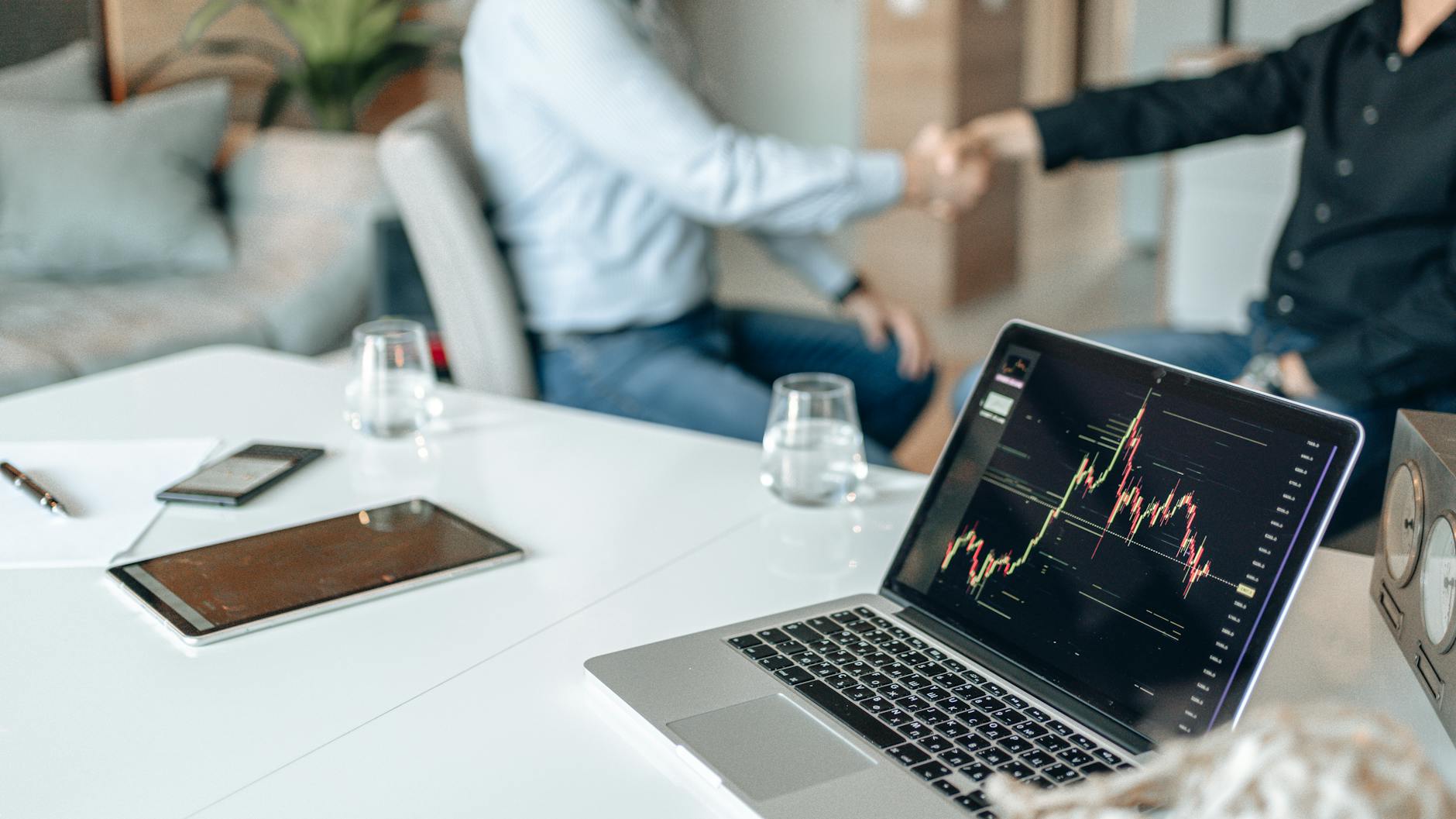 Handshake over financial laptop for Helsinki deal-purpose planning.