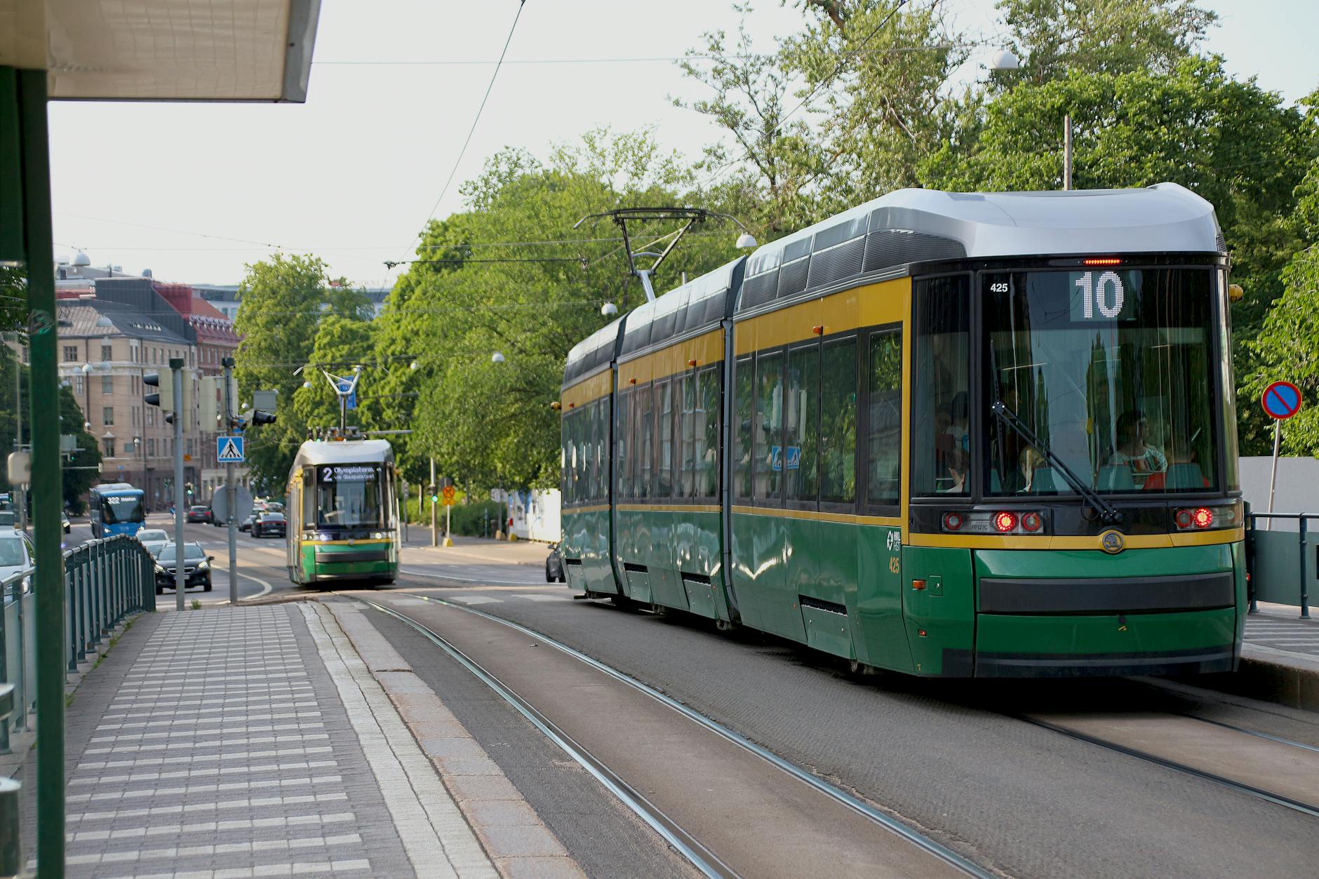 Two Helsinki trams on a sunny street for older traveler planning.