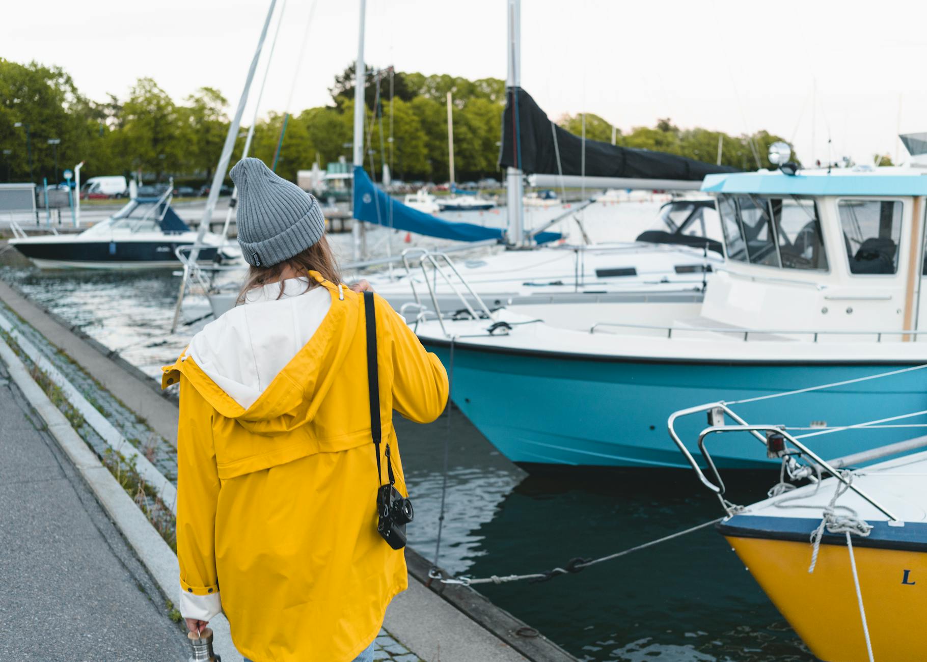 Woman in yellow jacket by Helsinki harbor for evening route planning.