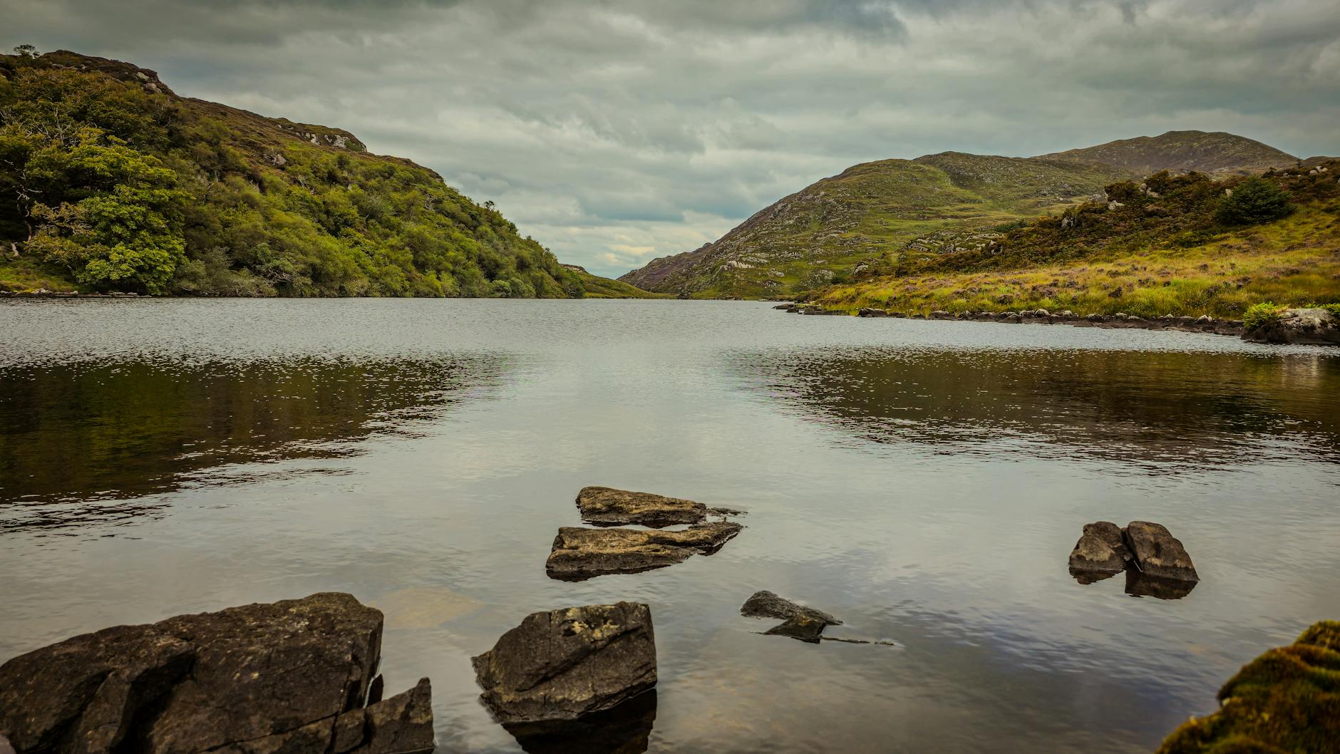 Serene view of a lake surrounded by lush green hills in Killarney National Park, Ireland.