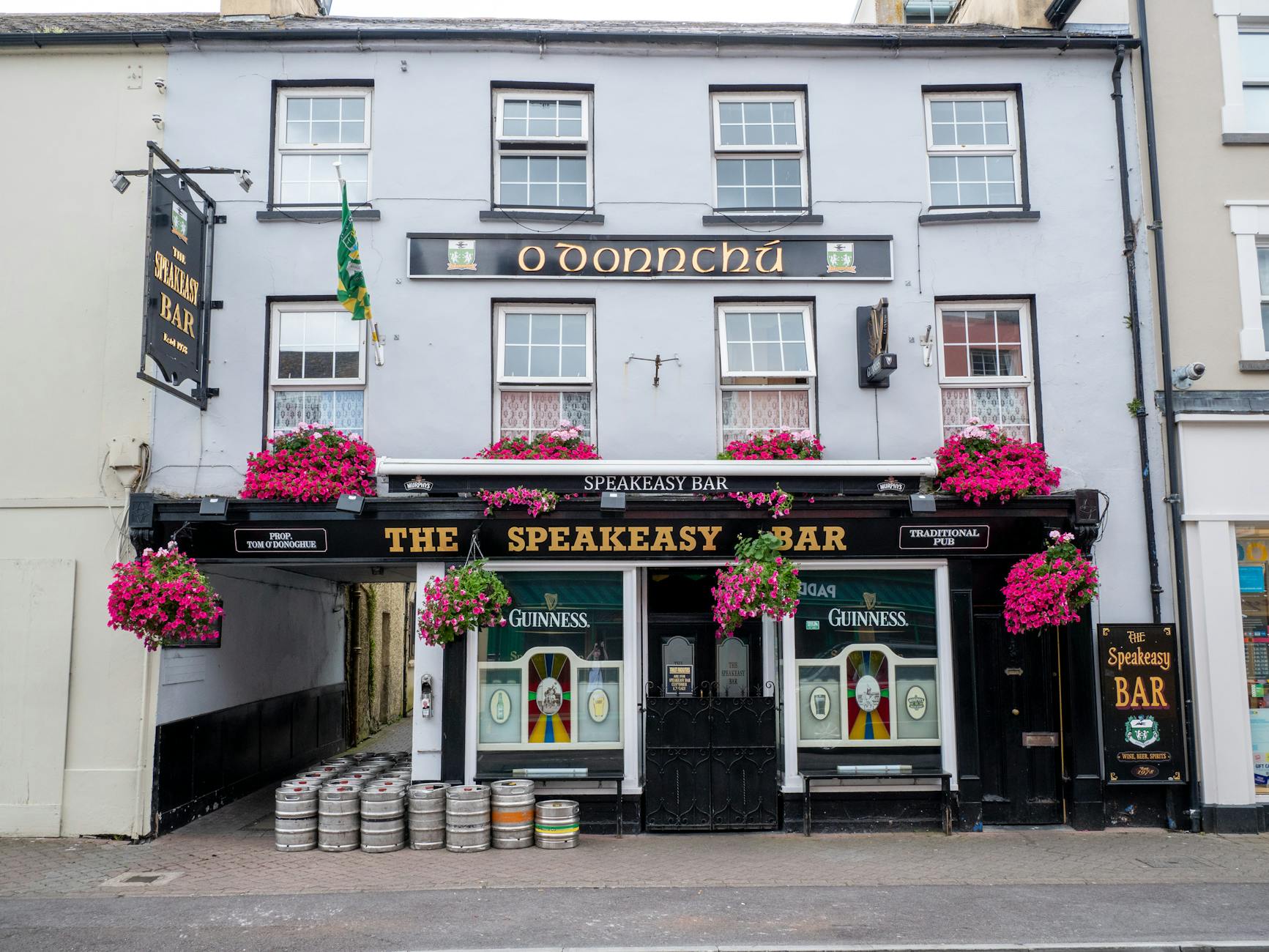 Colorful Irish speakeasy bar facade adorned with flowers in Killarney, Ireland.