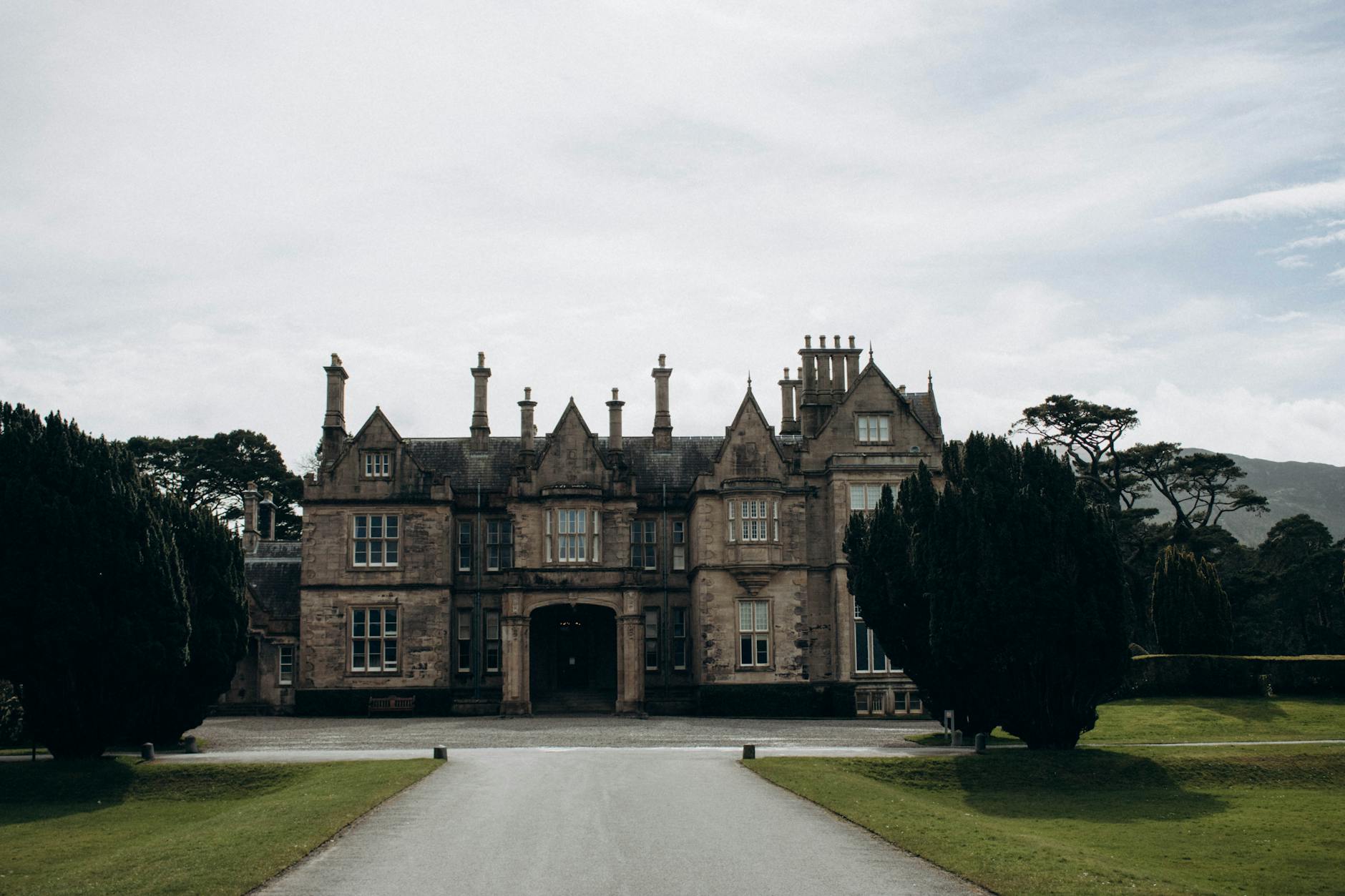Elegant exterior of Muckross House in Killarney, Ireland, framed by greenery.