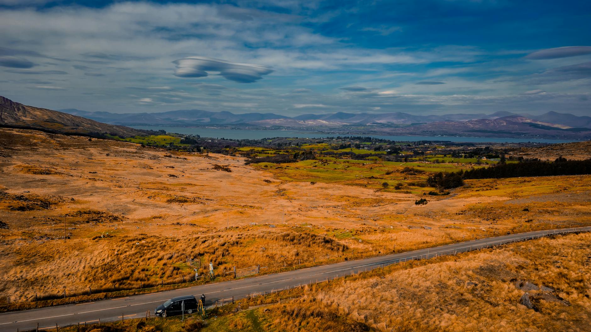 Stunning view of Ireland's natural landscape with mountains and road under a blue sky.