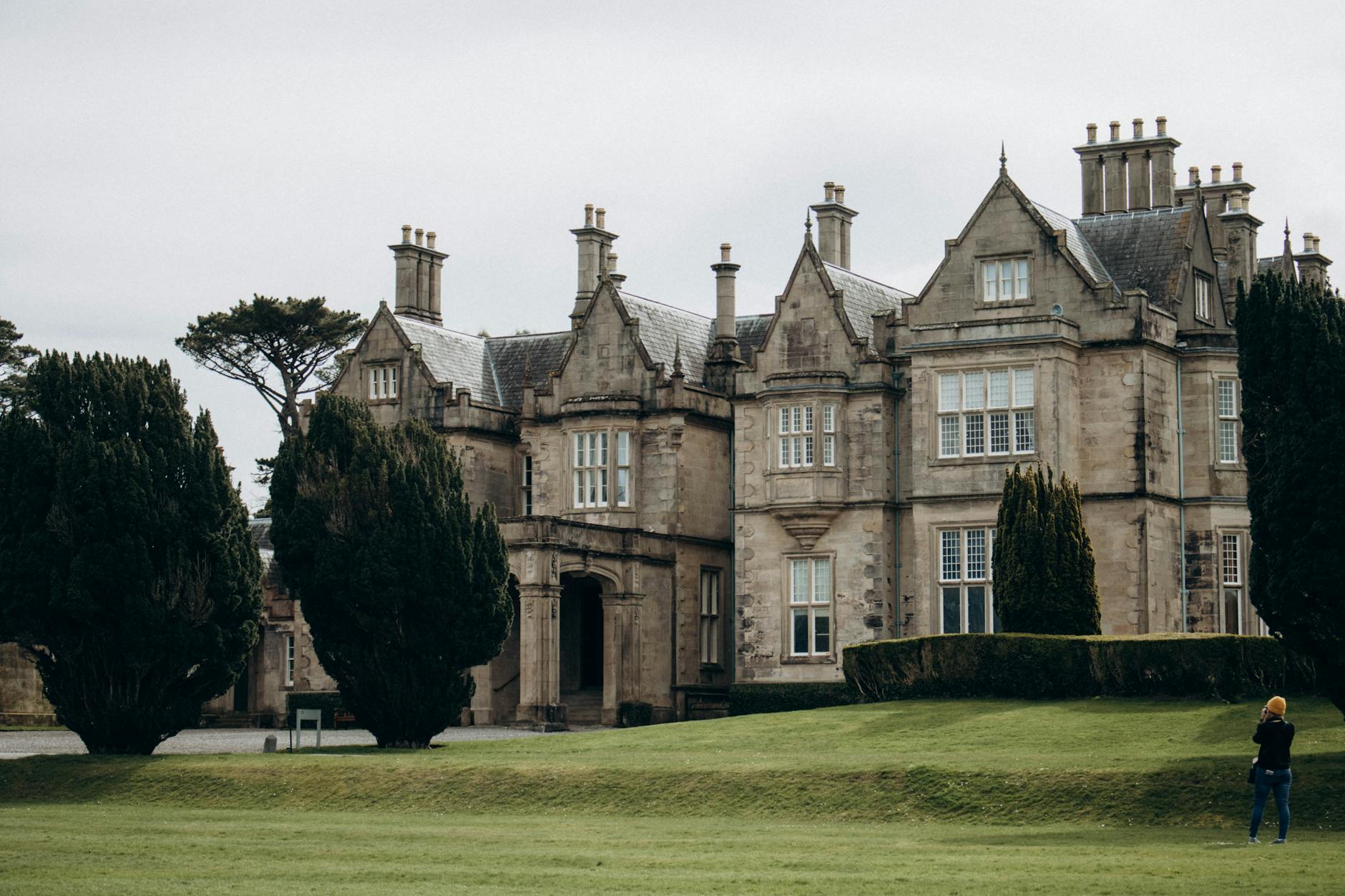 Historic Muckross House in Killarney, Ireland, surrounded by lush greenery.