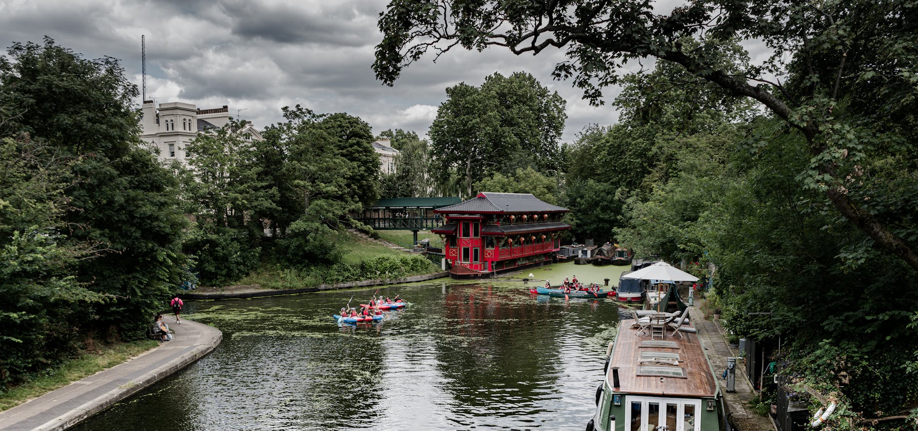 Kayakers on a London canal with greenery and buildings nearby