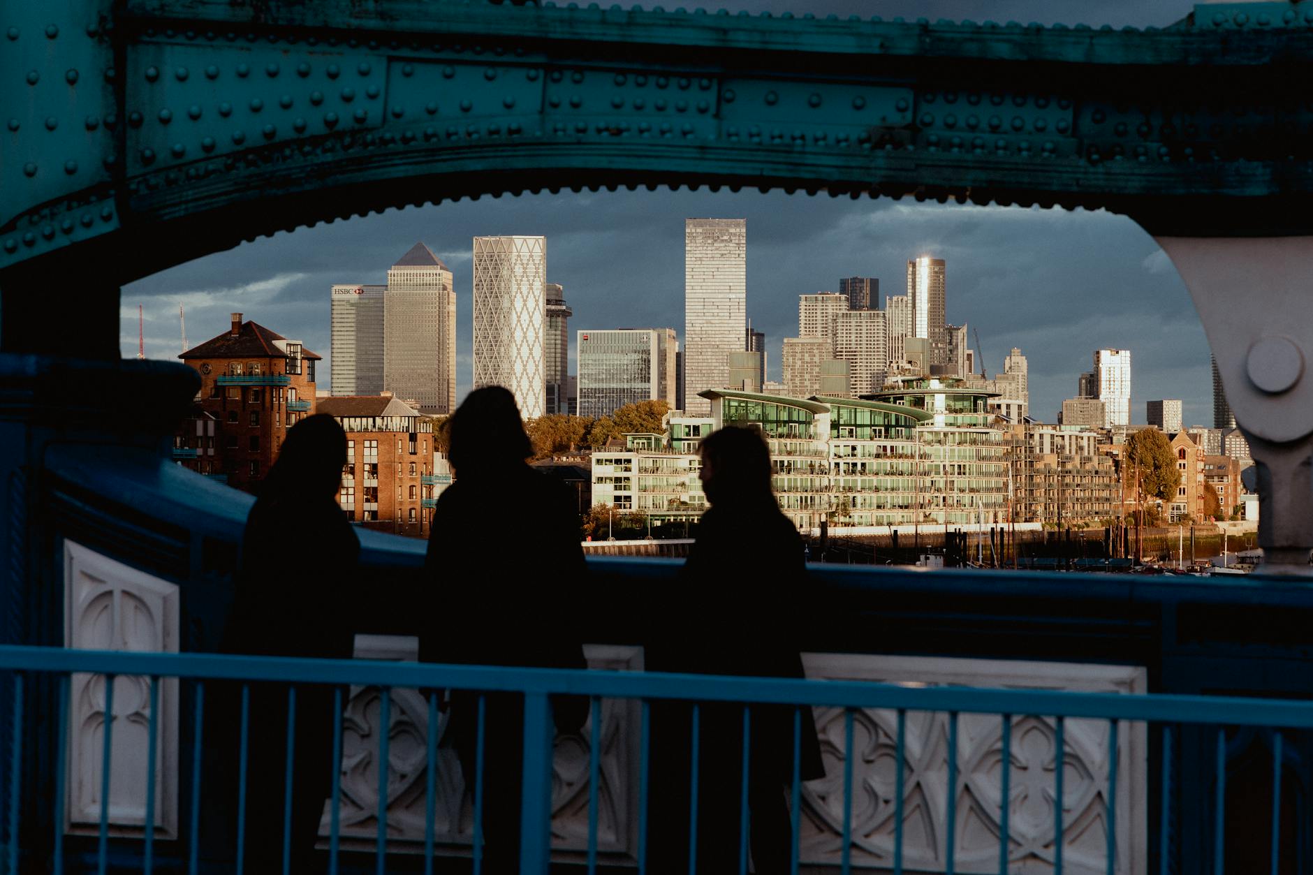 Silhouetted figures looking toward Canary Wharf at sunset