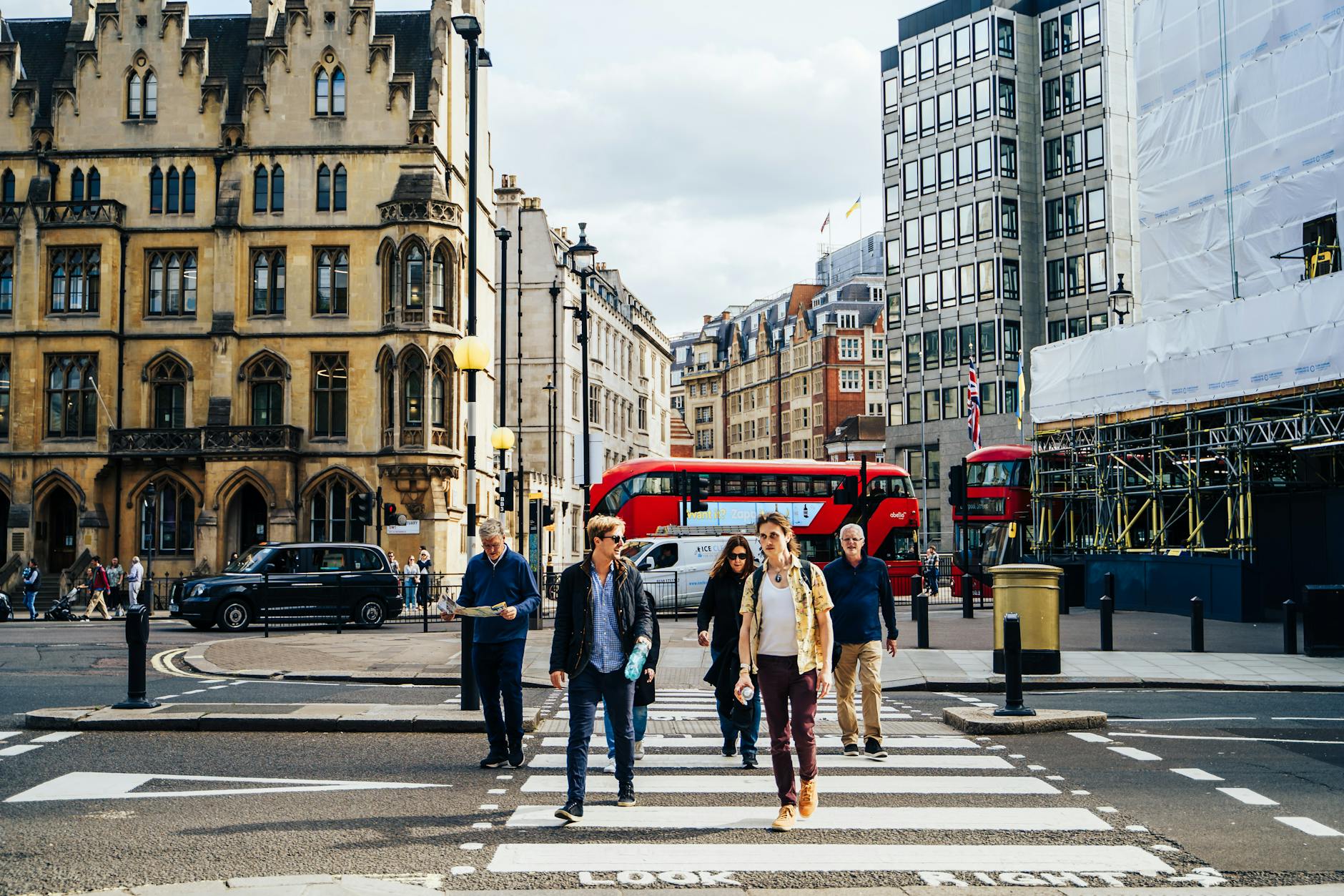 Busy London pedestrian crossing with red buses and central city crowds