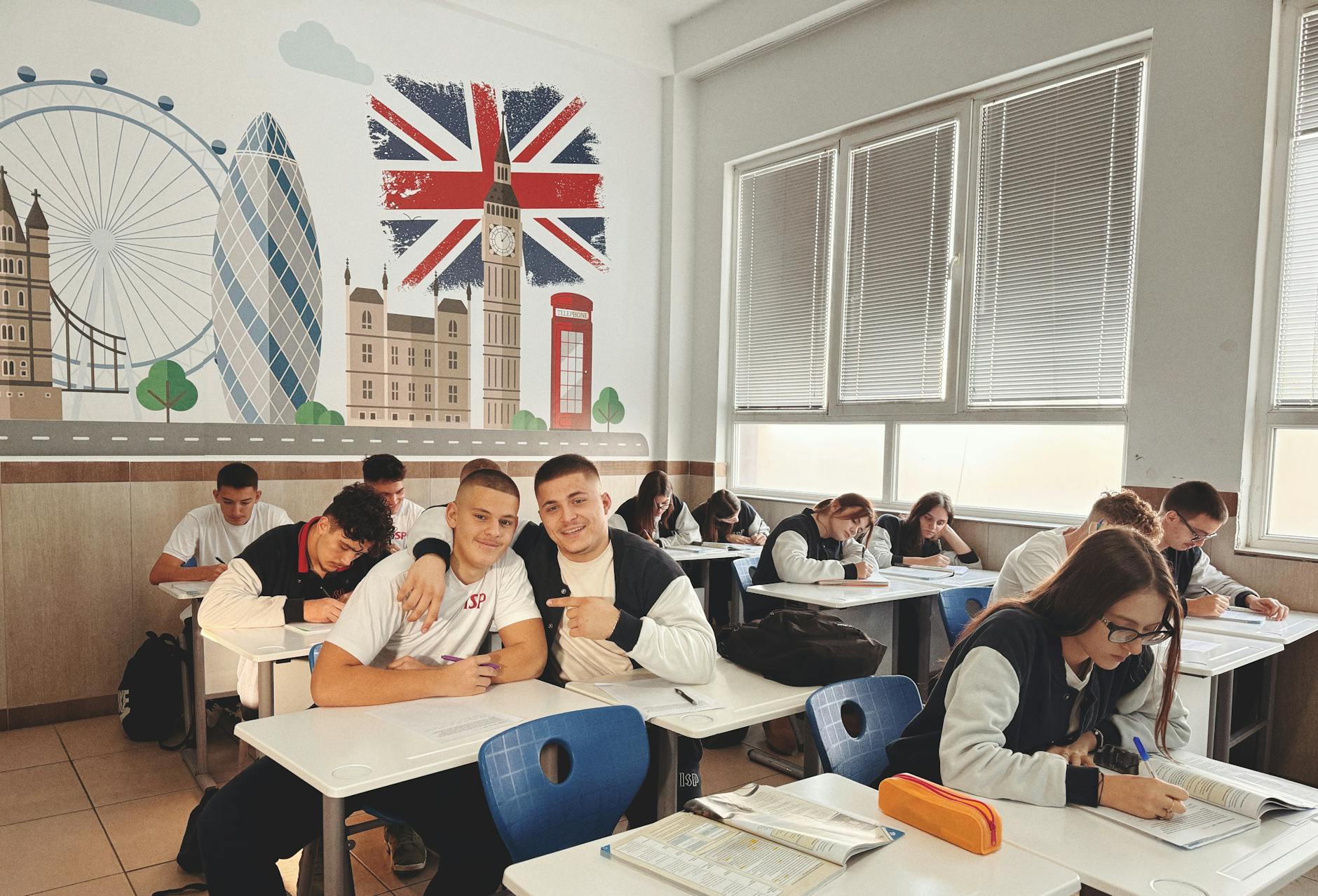 Students studying in a classroom with London landmarks and British flag mural