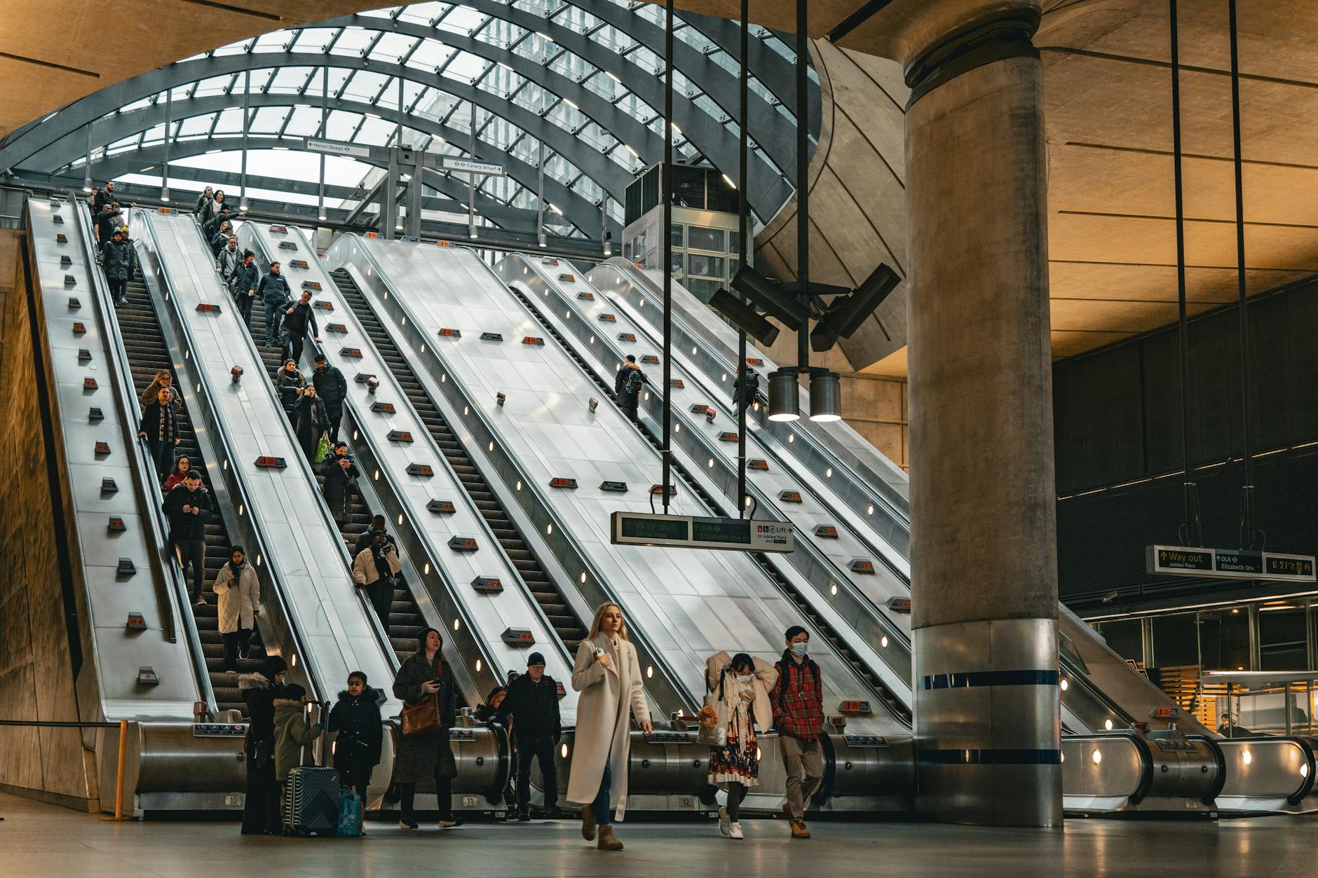 Escalators and commuters inside Canary Wharf Station in London