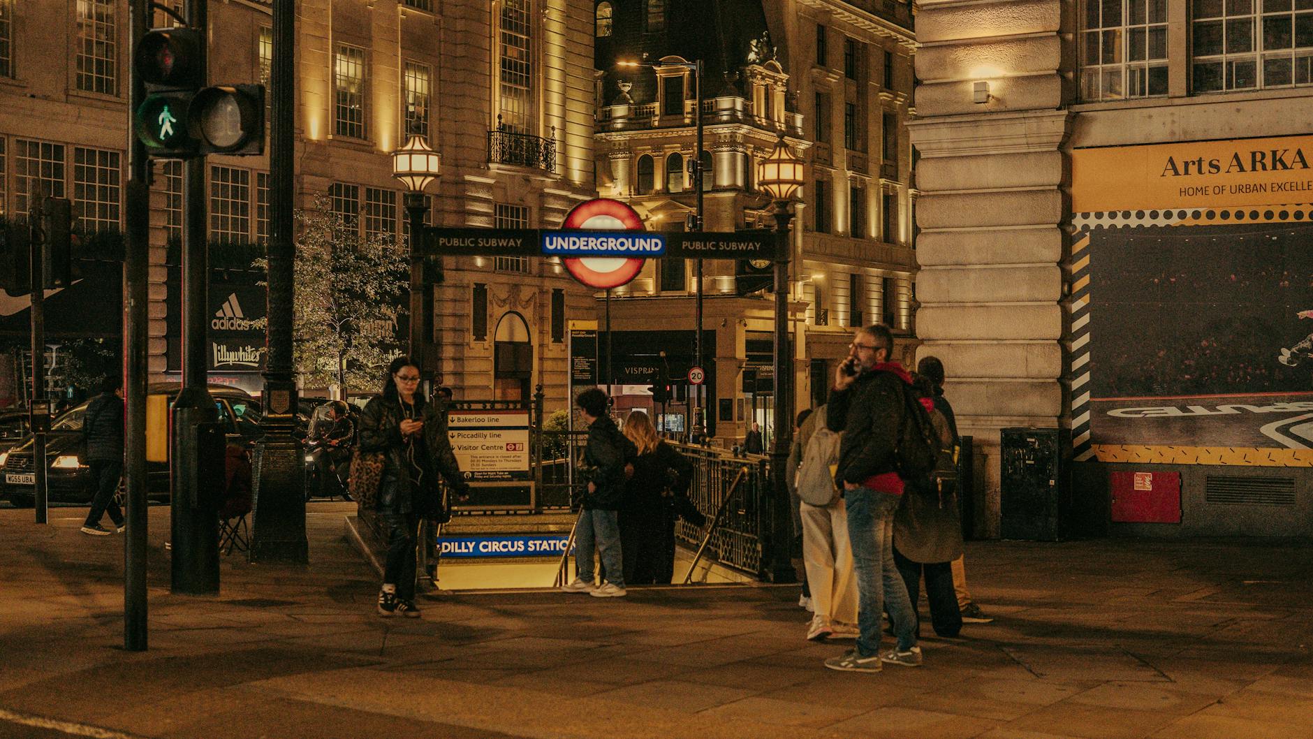 Piccadilly Circus station at night with lights and pedestrians