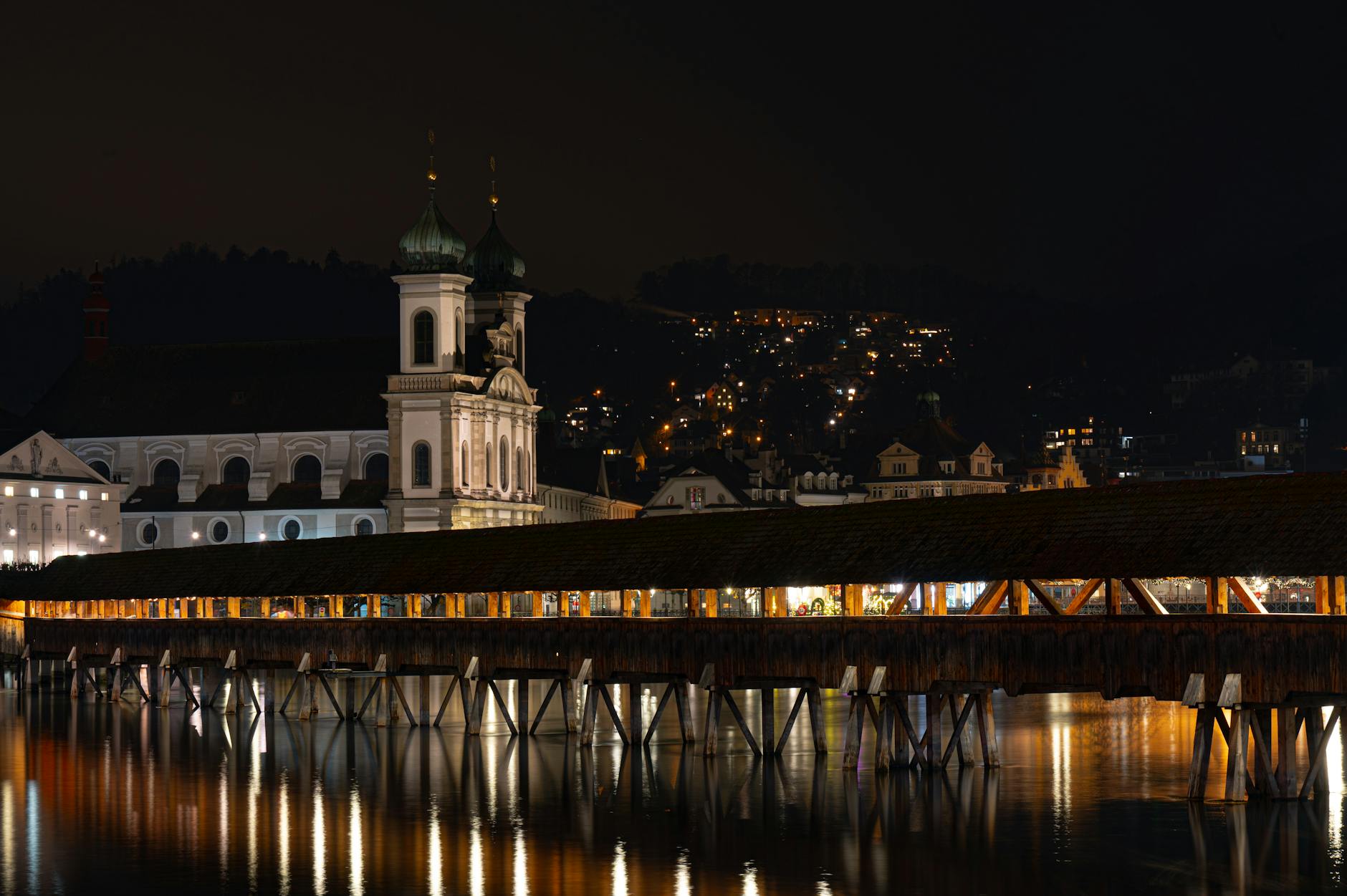 Chapel Bridge and Jesuit Church at night for journalist hotel base planning.