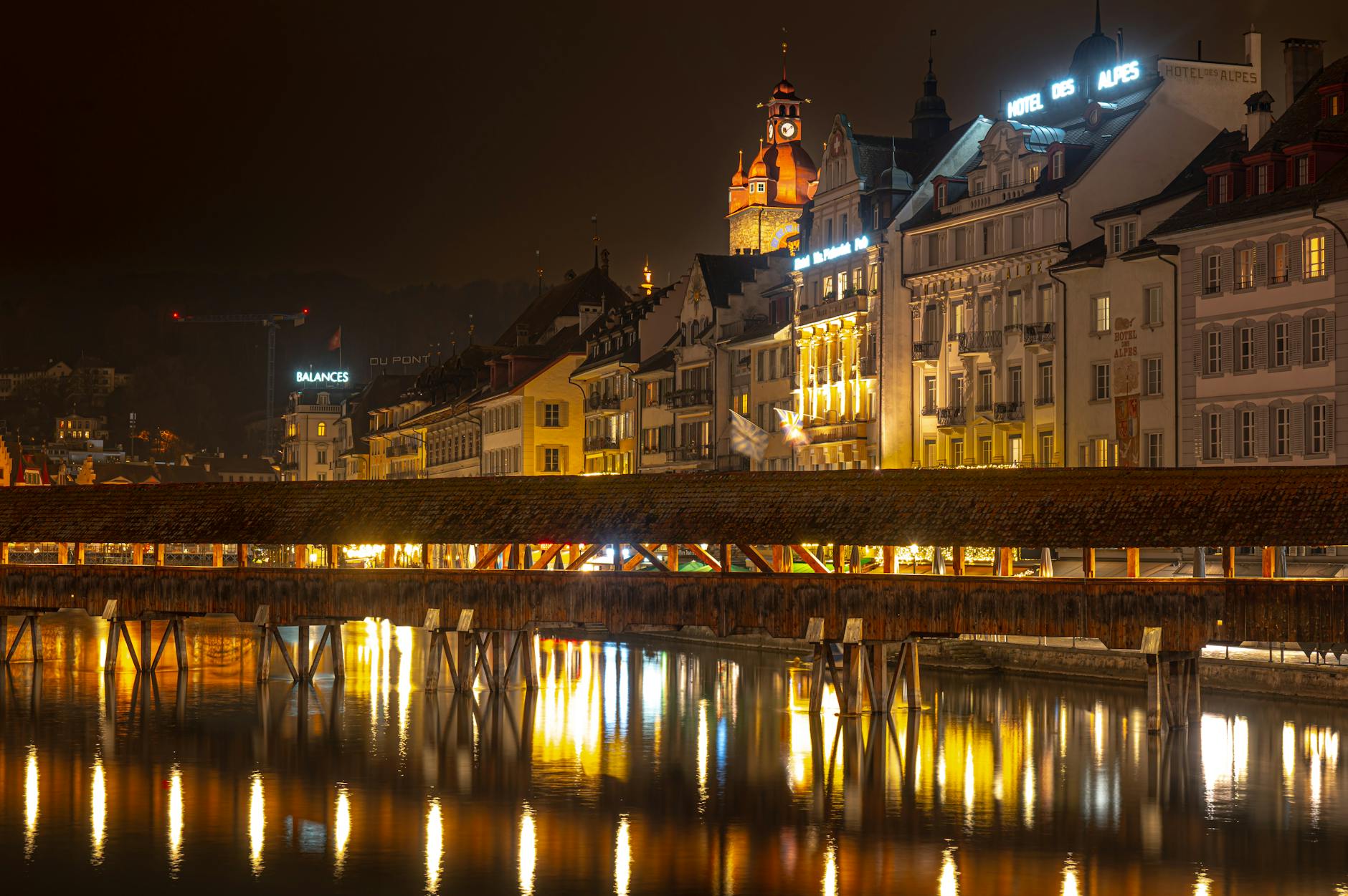 Illuminated Chapel Bridge in Lucerne for journalist arrival and evening coverage planning.