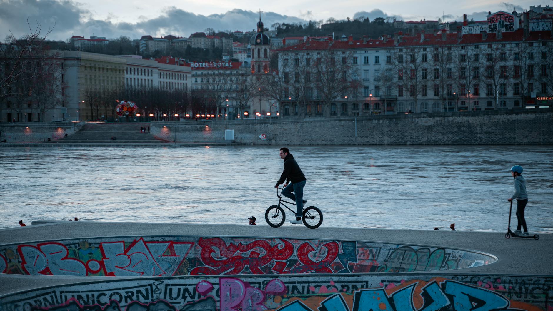 BMX cyclist riding beside a river at twilight