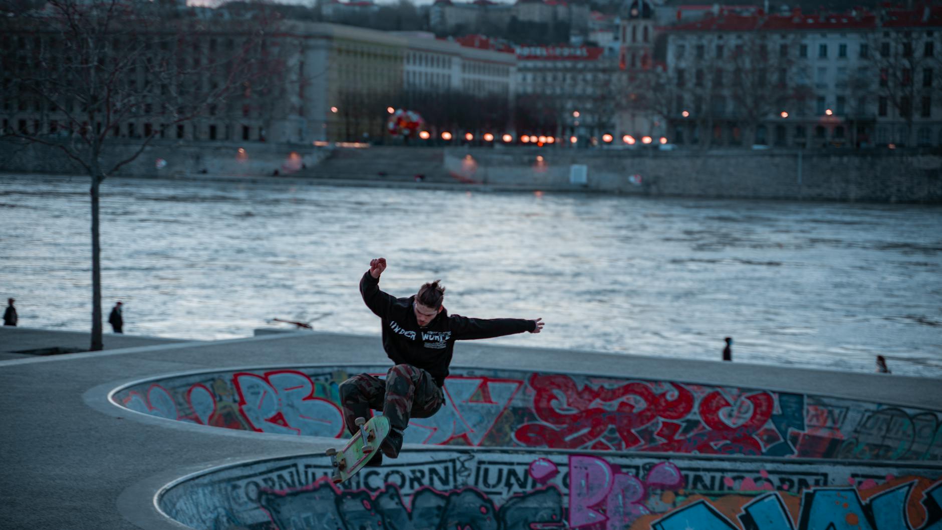 Skateboarder jumping at a riverfront skatepark in Lyon