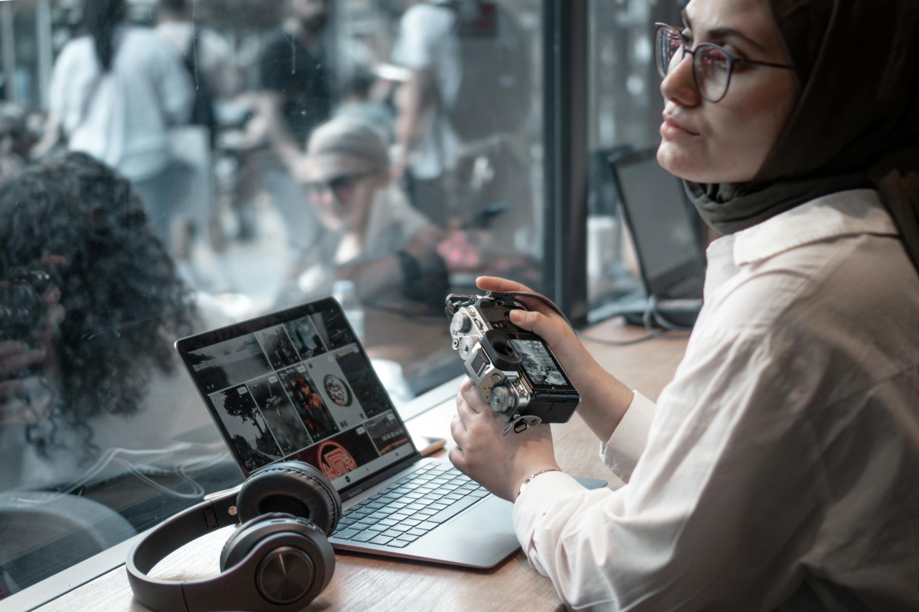 Creator working with a laptop and camera in a cafe