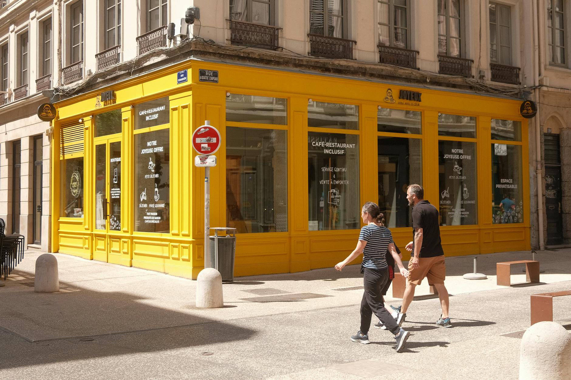 People walking past a yellow cafe in Lyon