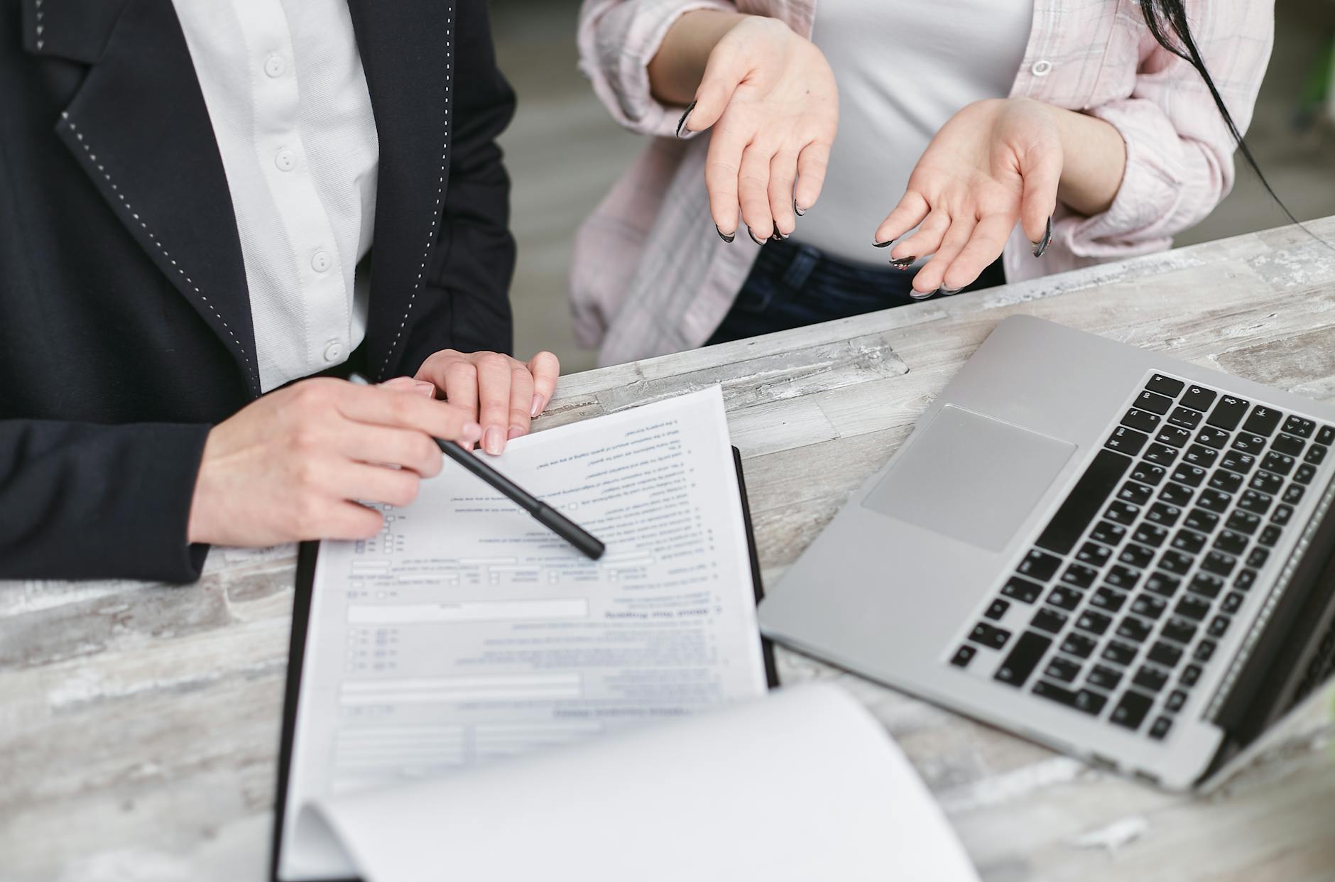 Professionals discussing a contract beside a laptop