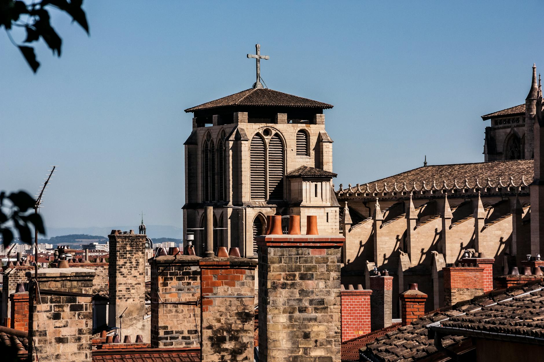 Historic church facade in Lyon with a cross and rooftops