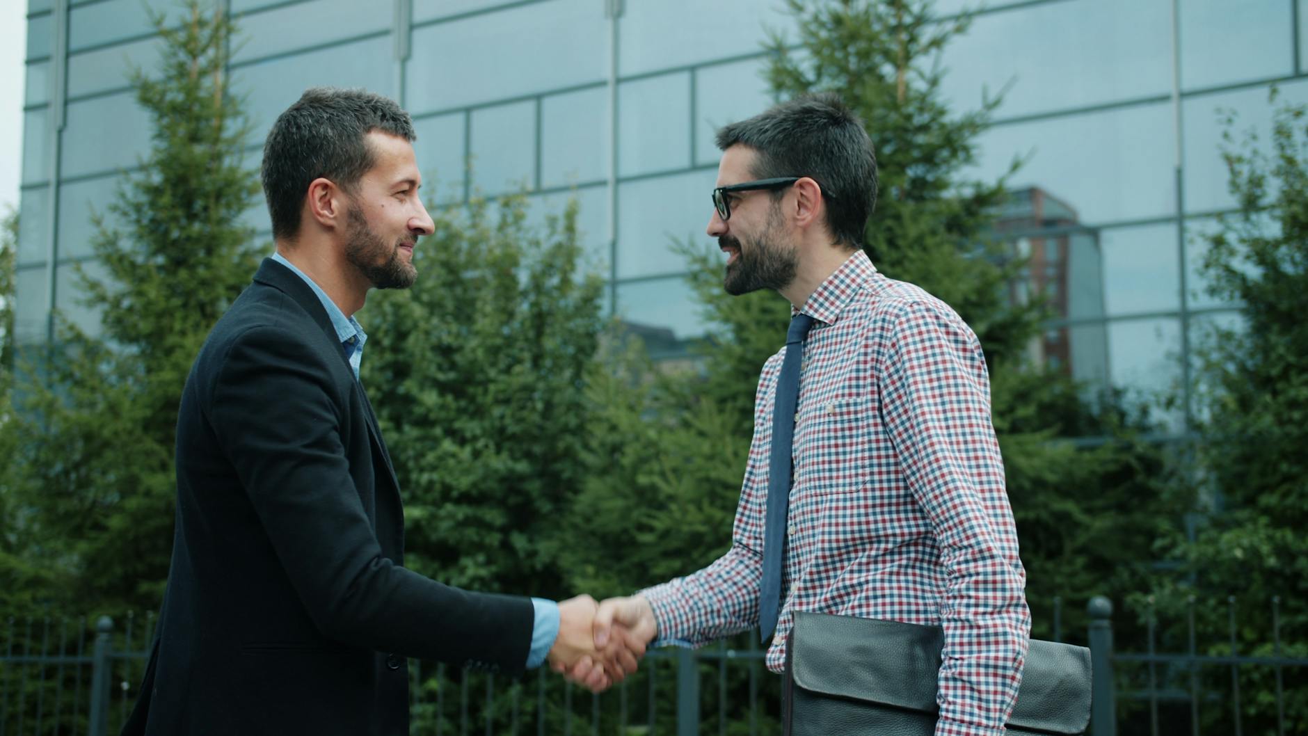 Businesspeople shaking hands outside an office building
