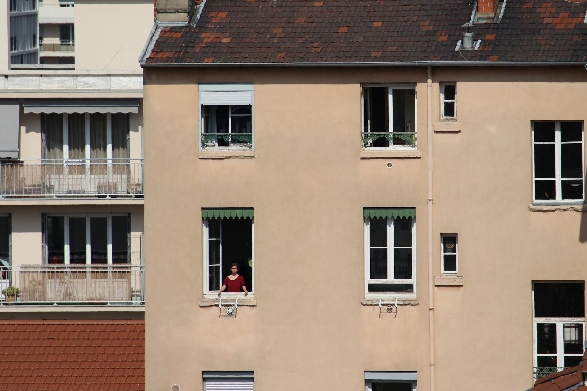 Woman standing at a window in a Lyon apartment building