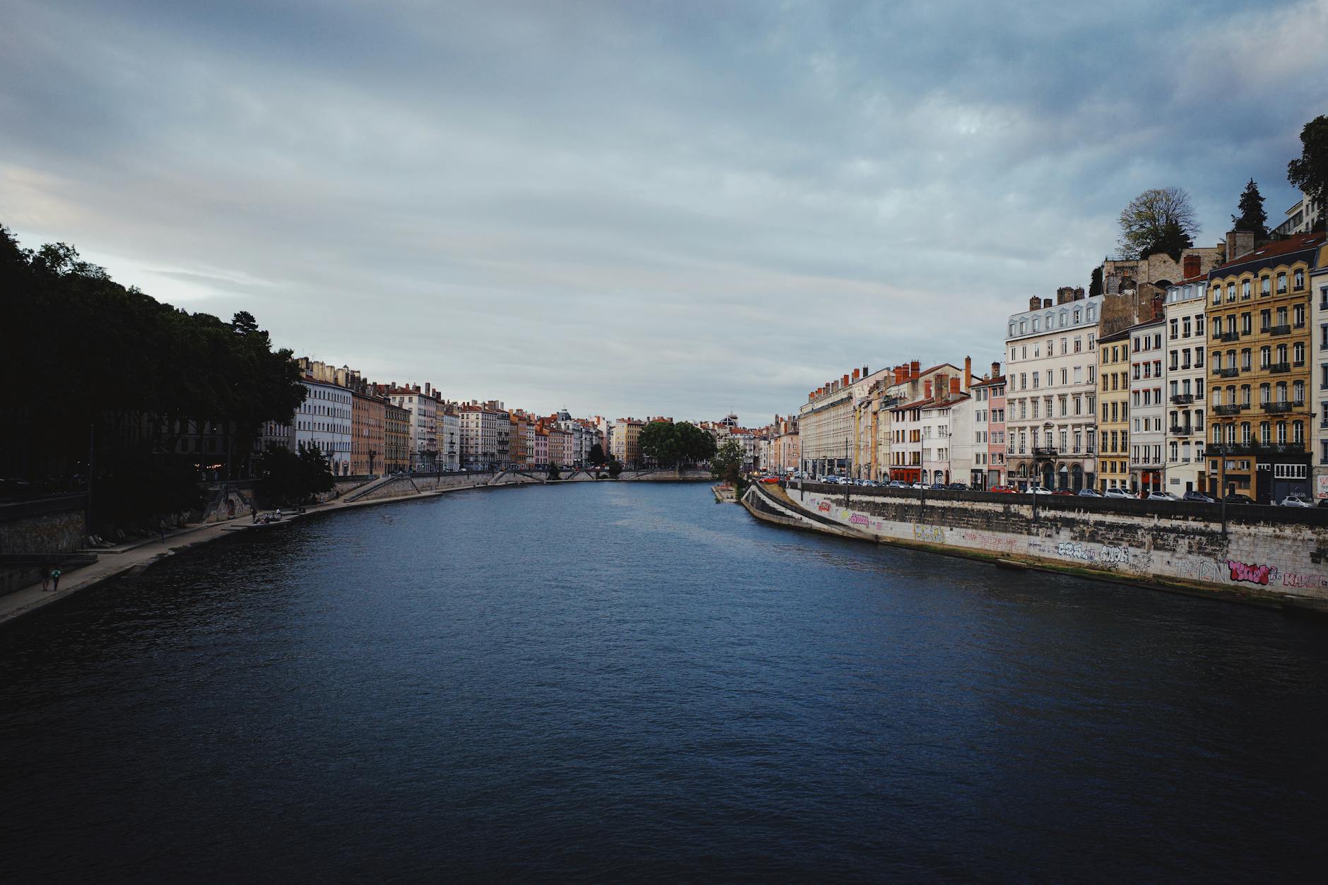 Riverfront architecture in Lyon under dramatic clouds