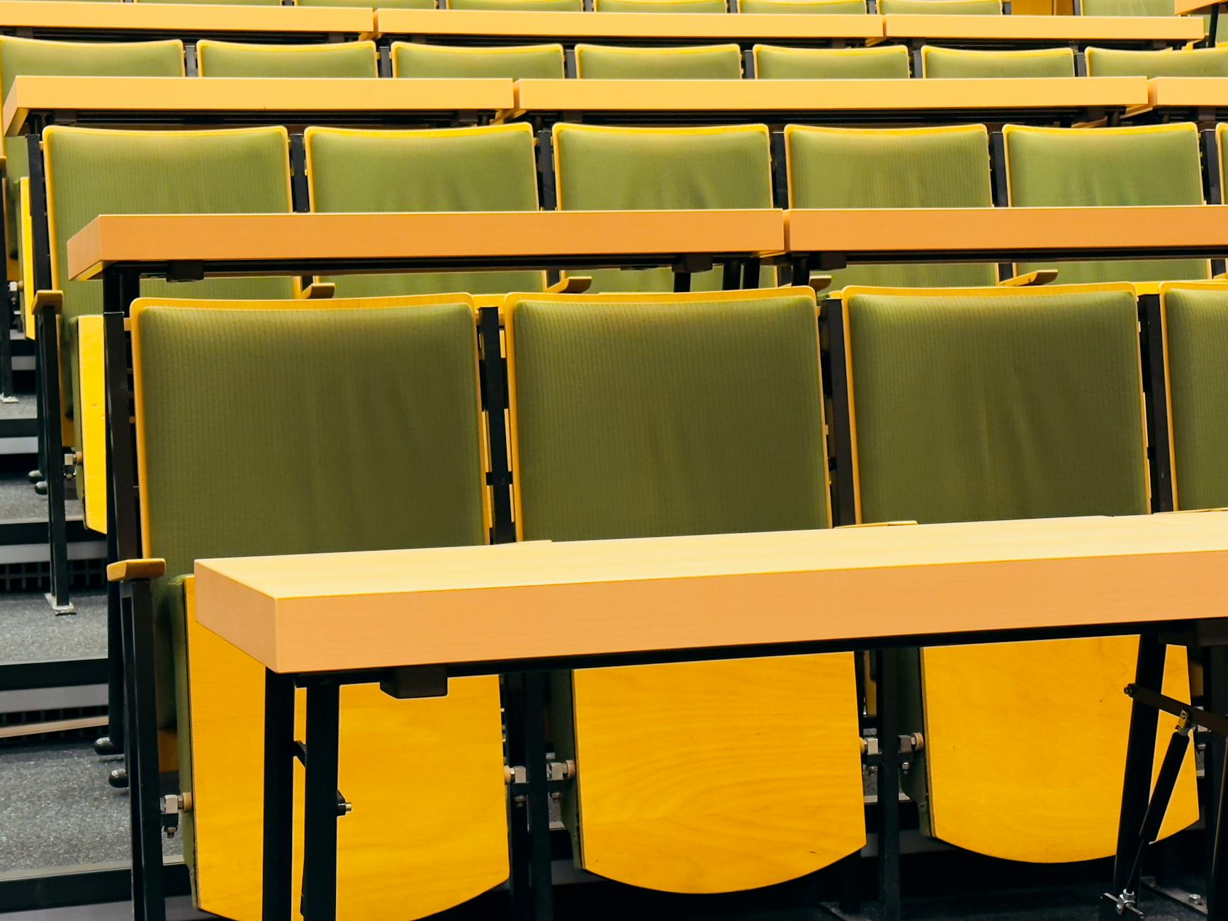 Modern lecture hall with green seats and wooden desks