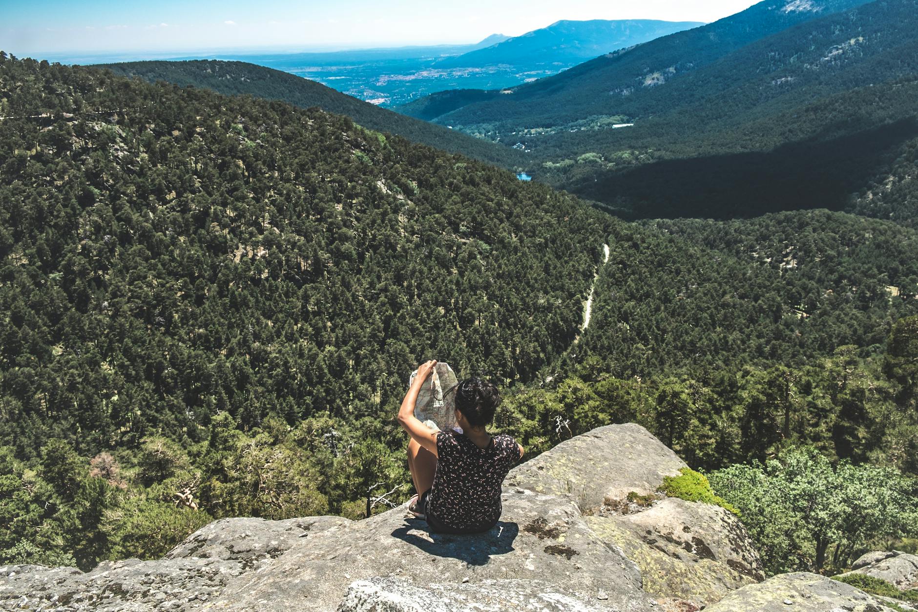 Person checking a map on a rock in the mountains near Madrid