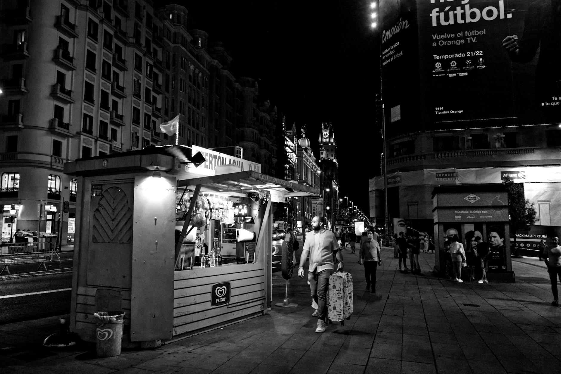 Night street in Madrid with a food stall and pedestrians