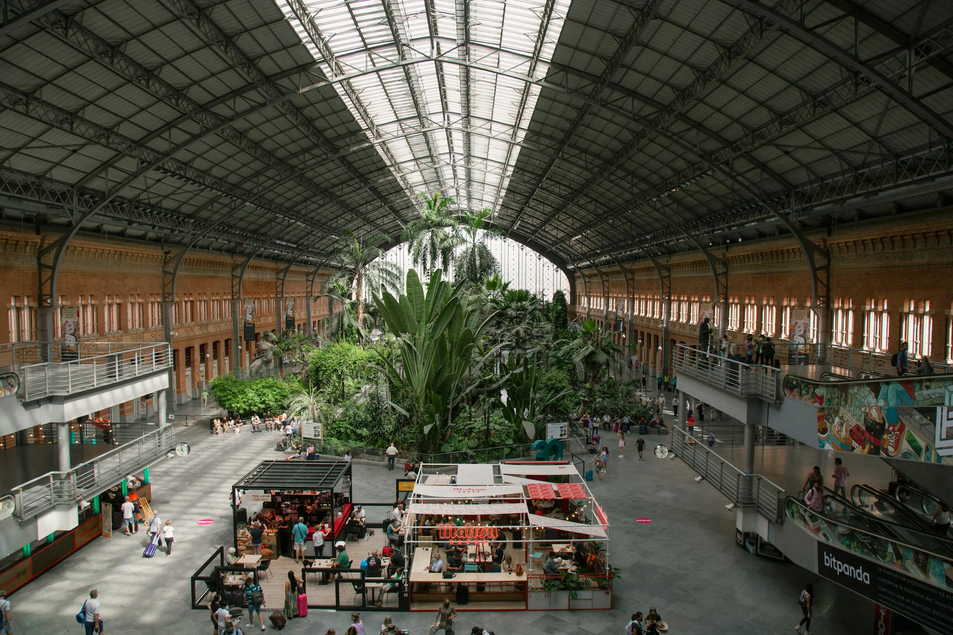 Interior of Madrid Atocha station with greenery and travelers