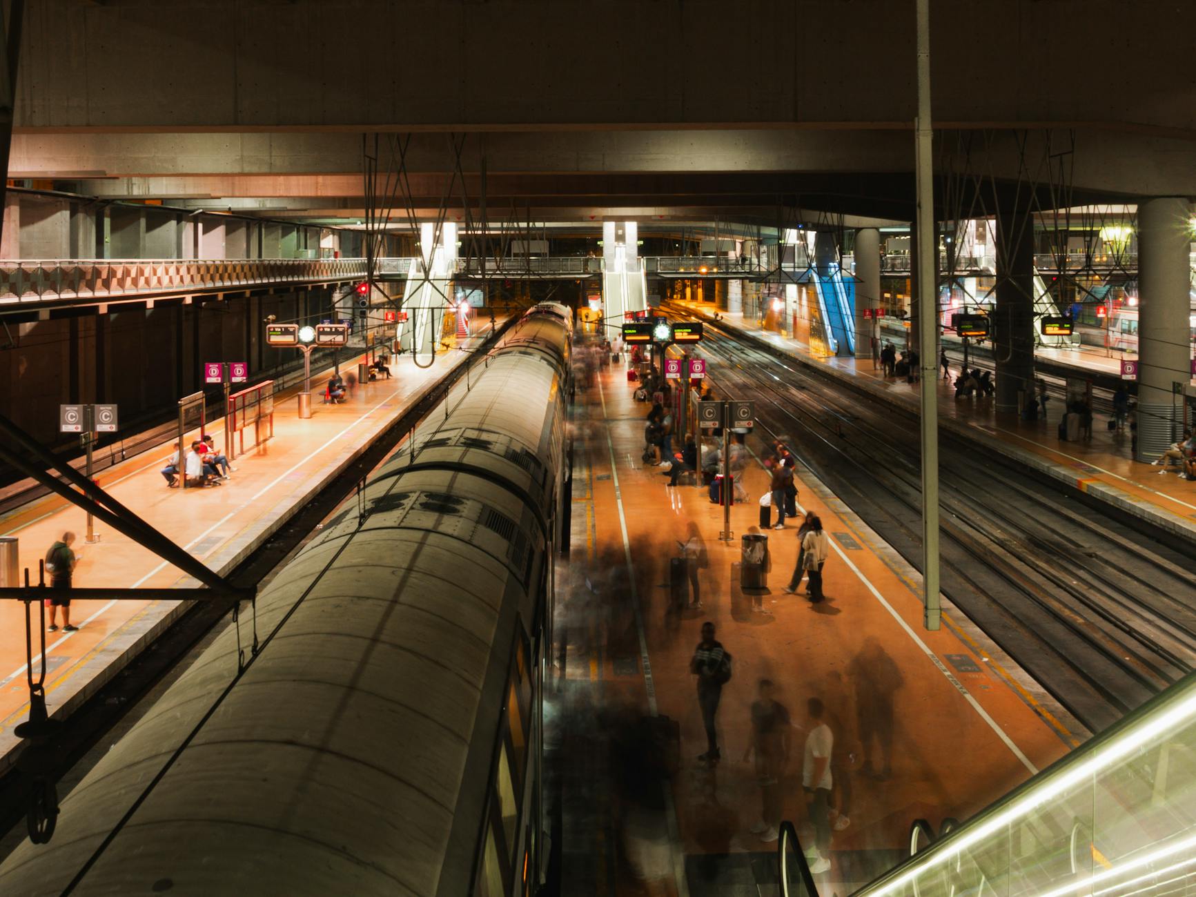 Blurred movement of travelers in a Madrid railway station at night