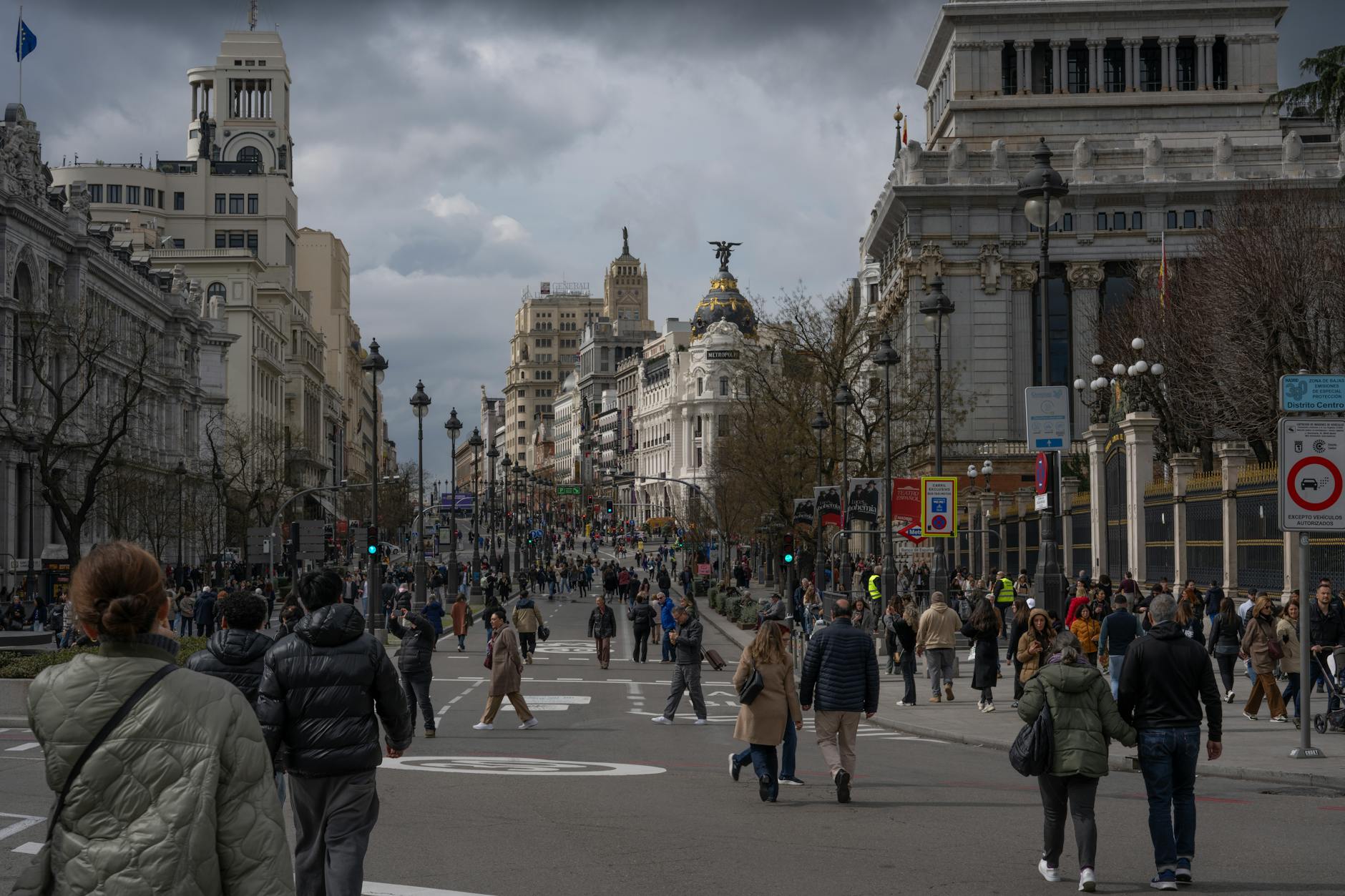 Busy Madrid city-center street with pedestrians and historic buildings