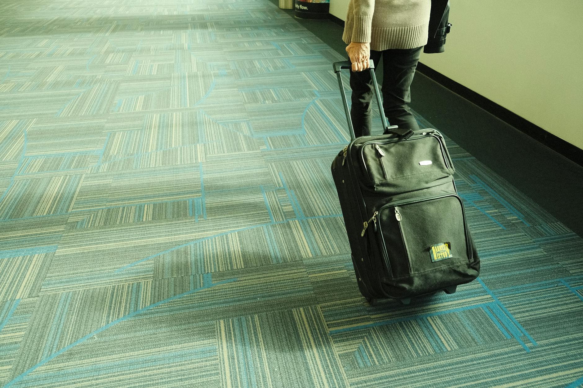 Traveler walking with luggage through an airport corridor