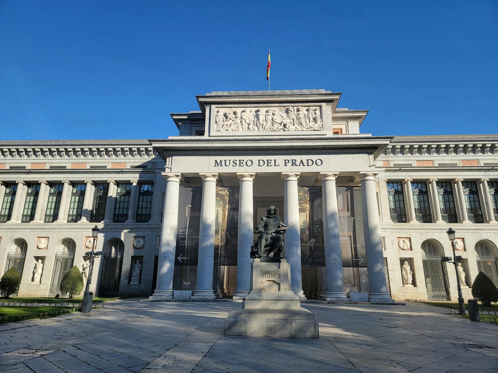 Facade of the Prado Museum under clear blue skies in Madrid